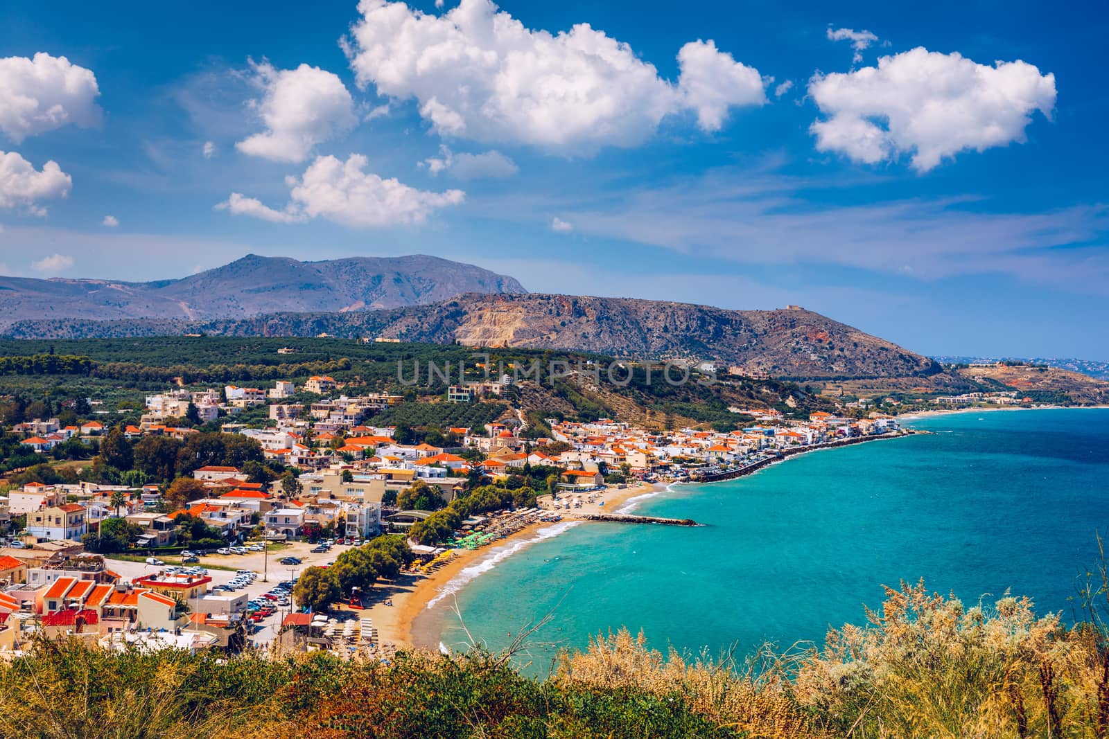 Greek holidays, beautiful Kalyves village with turquoise sea in Crete island, Greece. View of Kalyves beach, Crete. Tourists relaxing on the beach and views to the mountains, Kalyves, Crete, Greece