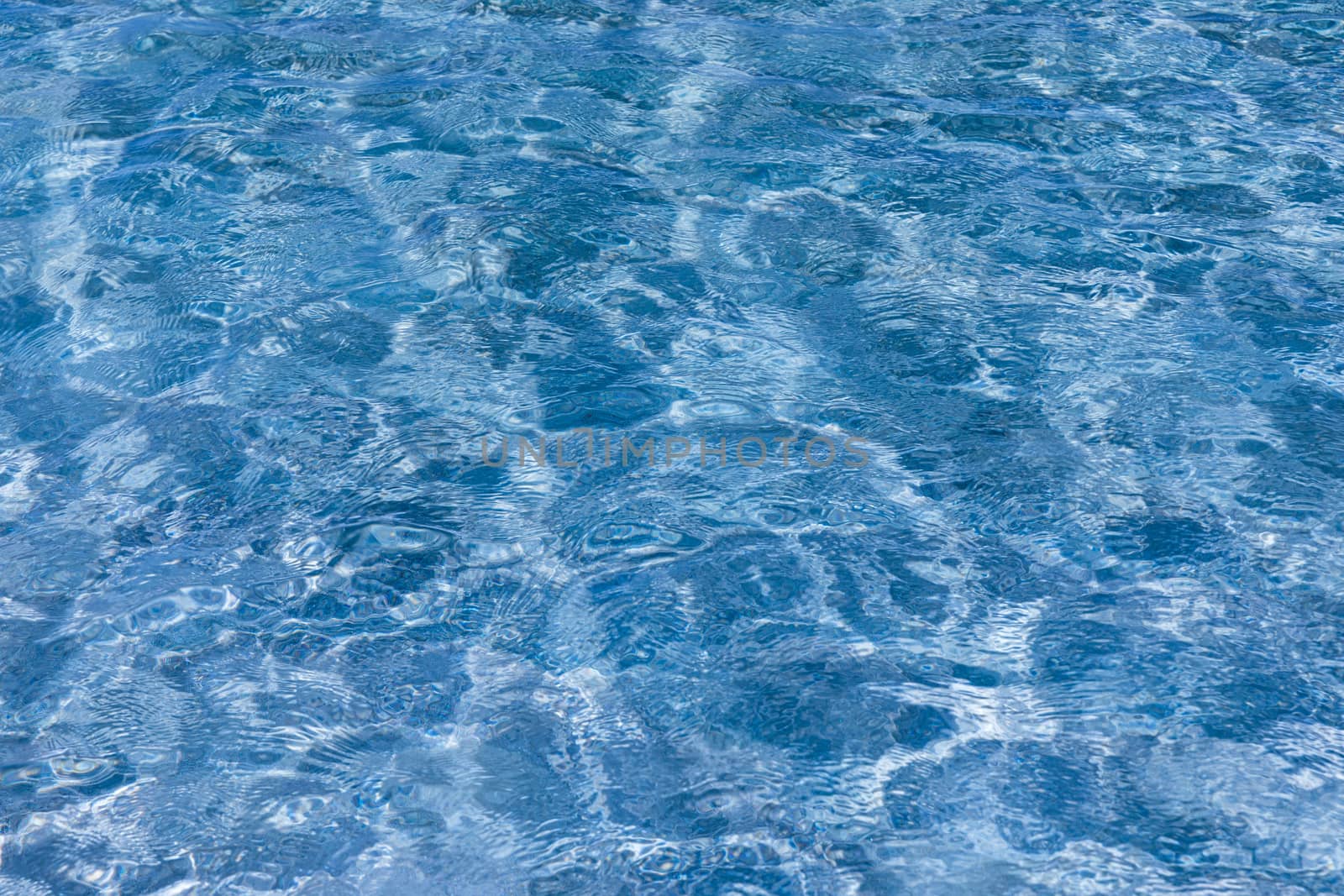 Water surface with bright sun light reflections, sea water background. Water surface with bright sun light reflections. Background of transparent sea water. Blue ripped sea water background.
