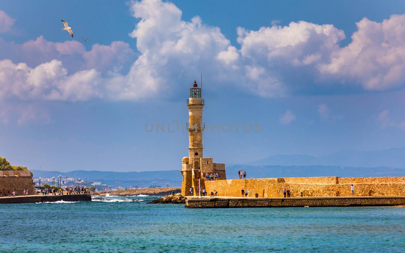 Venetian harbour and lighthouse in old harbour of Chania with seagulls flying over, Crete, Greece. Old venetian lighthouse in Chania, Greece. Lighthouse of the old Venetian port in Chania, Greece.