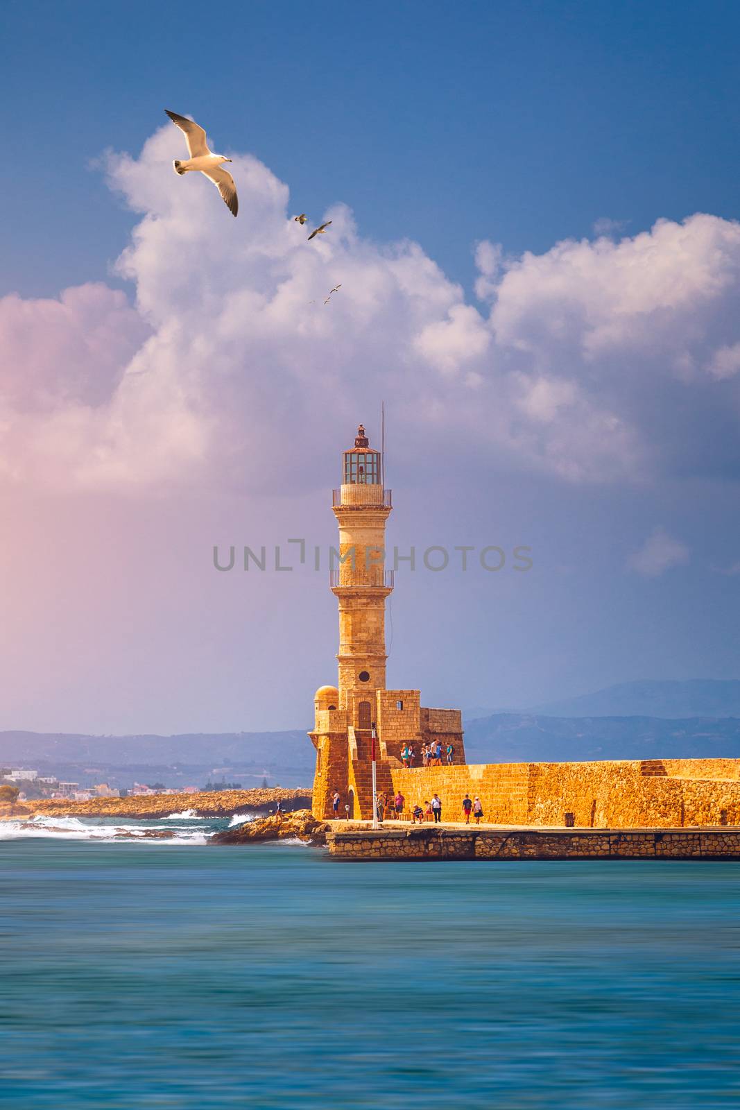 Venetian harbour and lighthouse in old harbour of Chania with seagulls flying over, Crete, Greece. Old venetian lighthouse in Chania, Greece. Lighthouse of the old Venetian port in Chania, Greece.