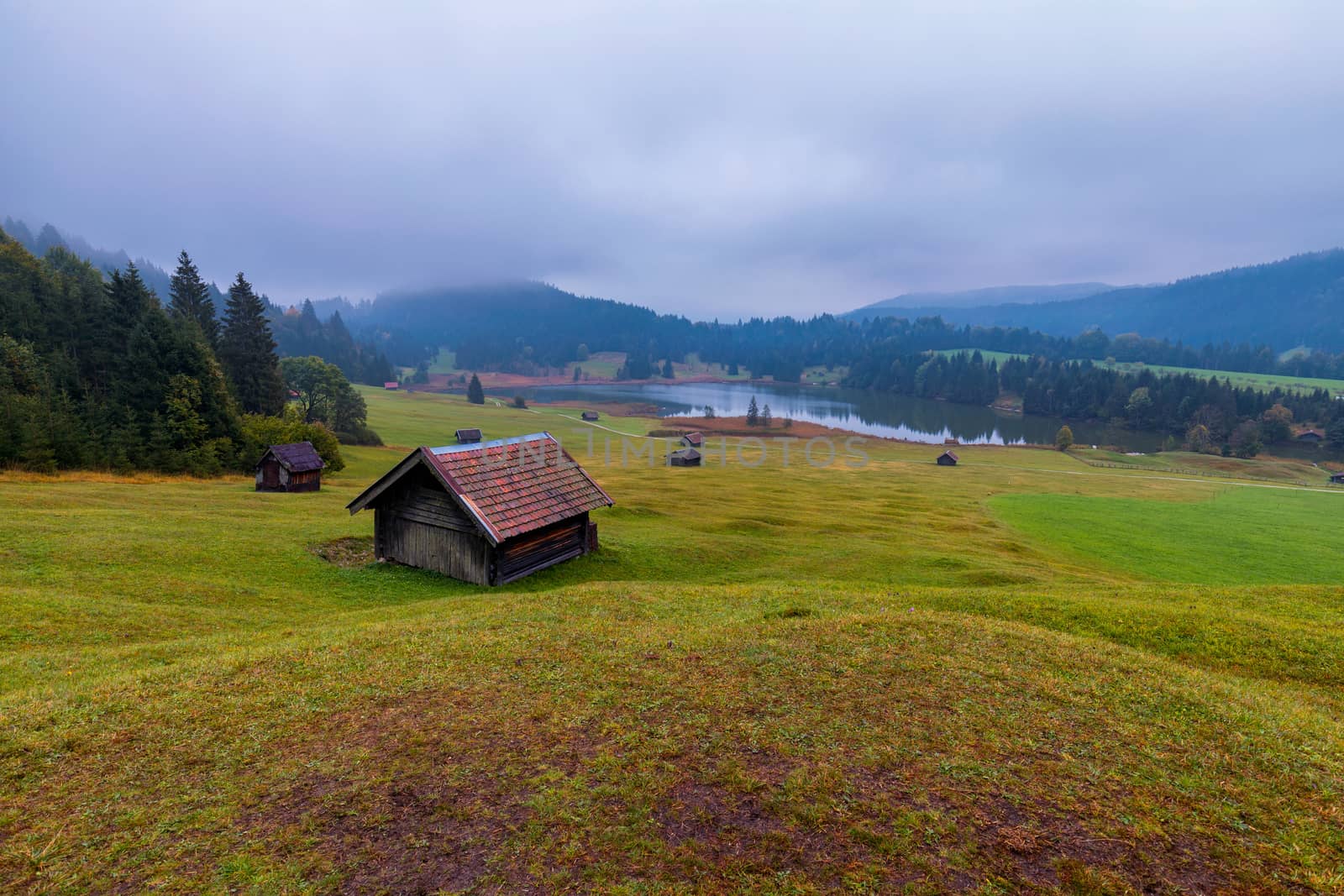 Panoramic morning scene of Wagenbruchsee (Geroldsee) lake with Zugspitze mountain range on background. Amazing autumn view of Bavarian Alps, Germany, Europe. Wooden hut on meadow by Geroldsee lake. 