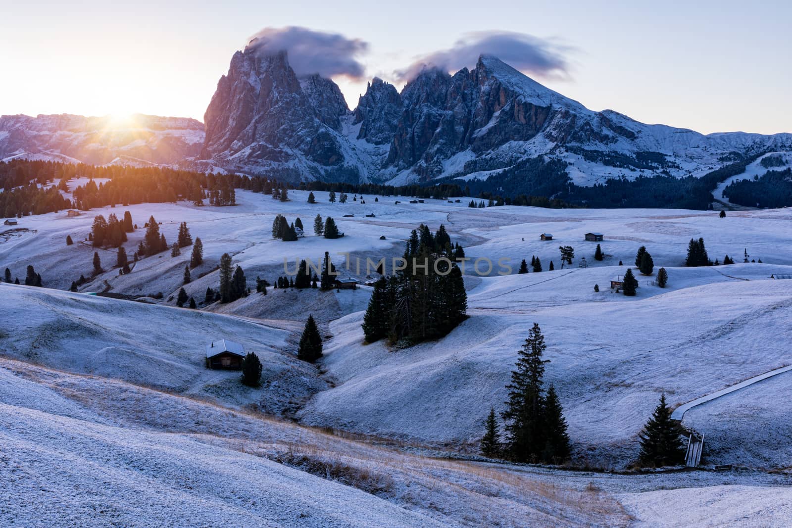 Small wooden farm house, cottage or log cabins on meadow on Alpe di Siusi, Seiser Alm. Alpe di Siusi or Seiser Alm with Sassolungo, Langkofel mountain group, Dolomite Alps, South Tyrol, Italy.