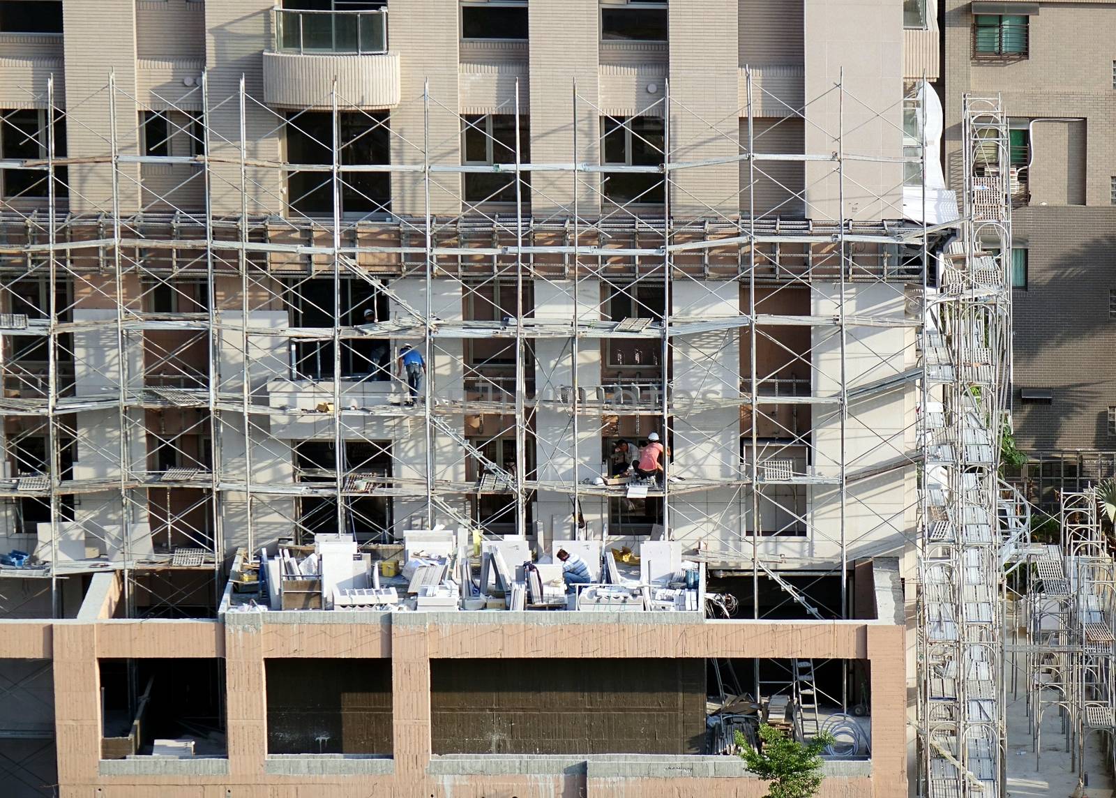 KAOHSIUNG, TAIWAN -- APRIL 18, 2015: Construction workers are working on the facade of a new apartment building in the city.