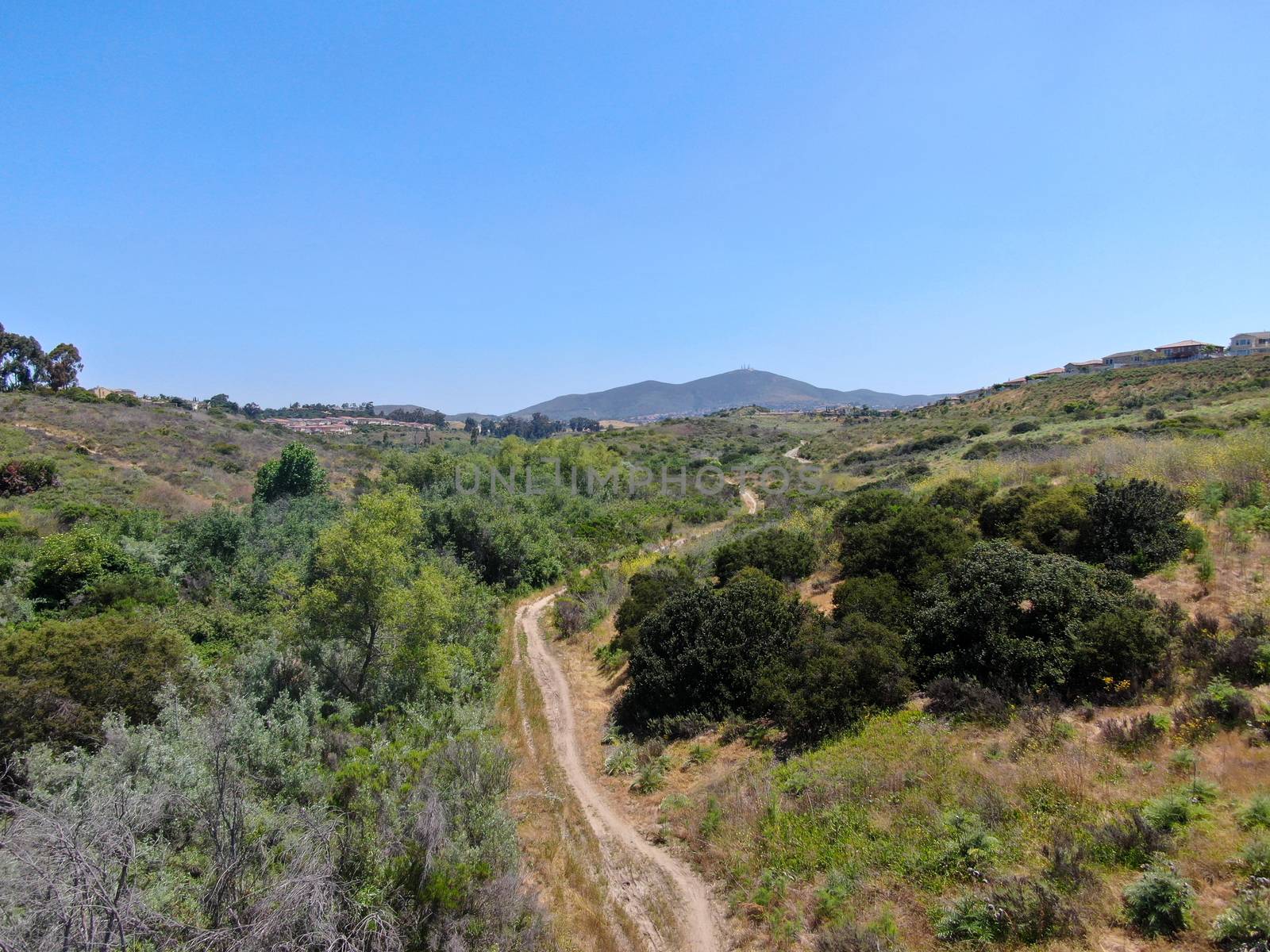 Aerial view of small dusty trail in green valley, San Diego, California, USA