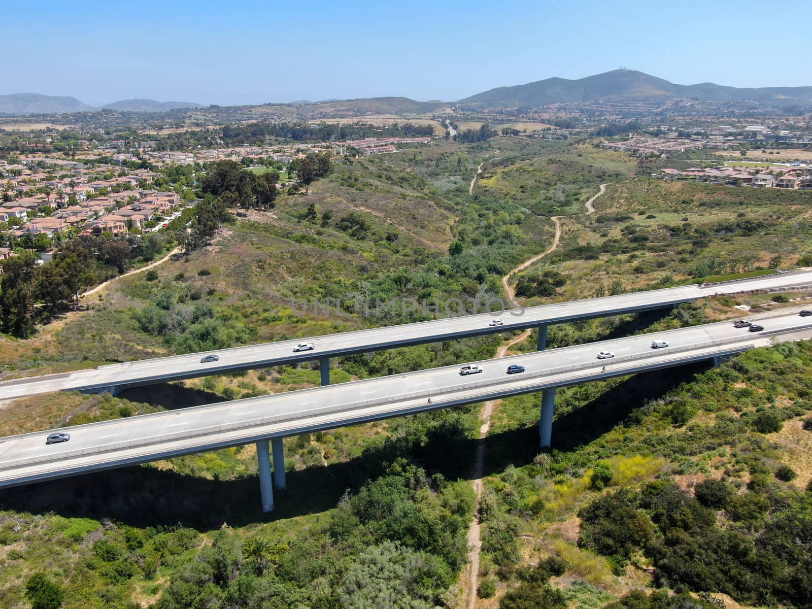 Aerial view of road highway bridge, viaduct supports in the valley among the green hills, transport infrastructure. California, USA 