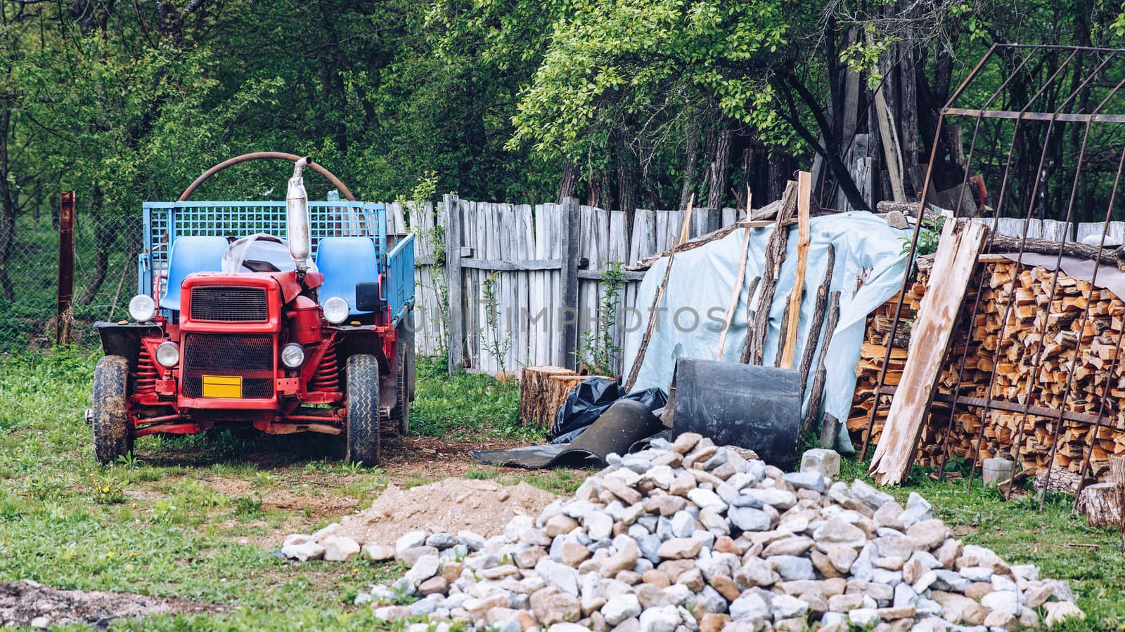 Rural scene of a backyard with tractor and wood pile