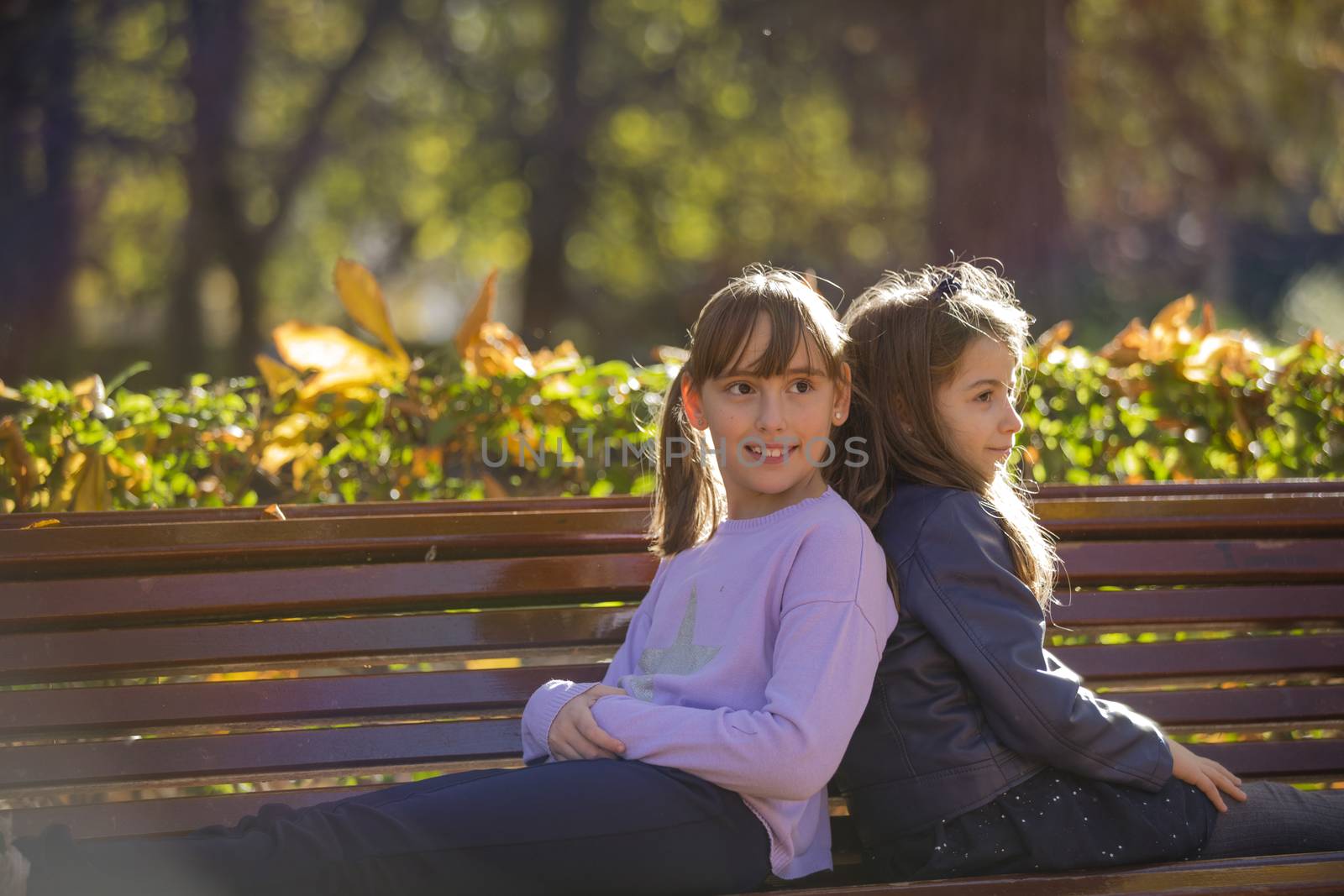 Two girlfriends having fun in a public park in the fall.