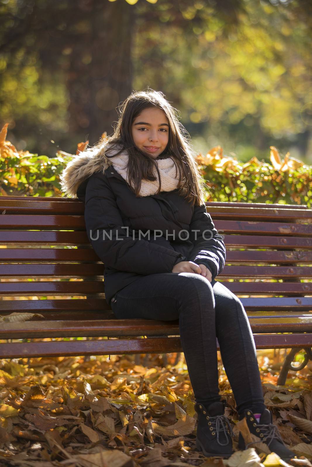 Beautiful girl in the park during the fall in a bench.
