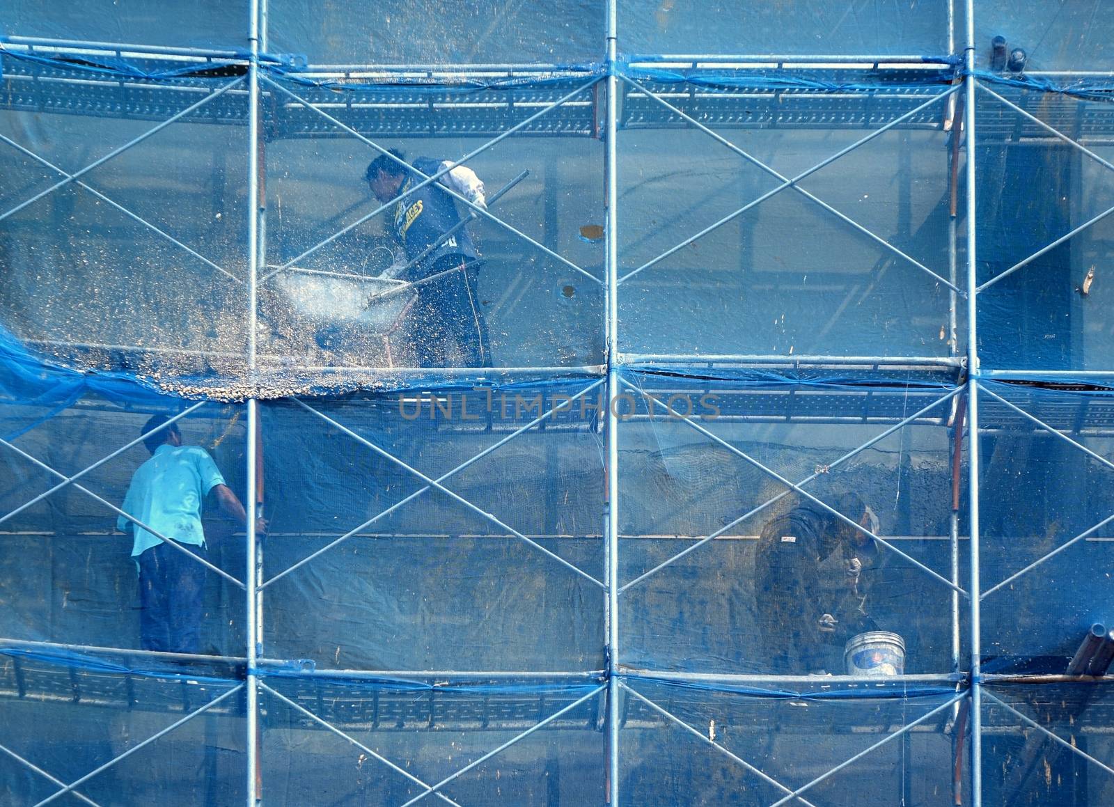 KAOHSIUNG, TAIWAN -- OCTOBER 5, 2014: Unidentified construction workers work on a new building on narrow scaffolding.