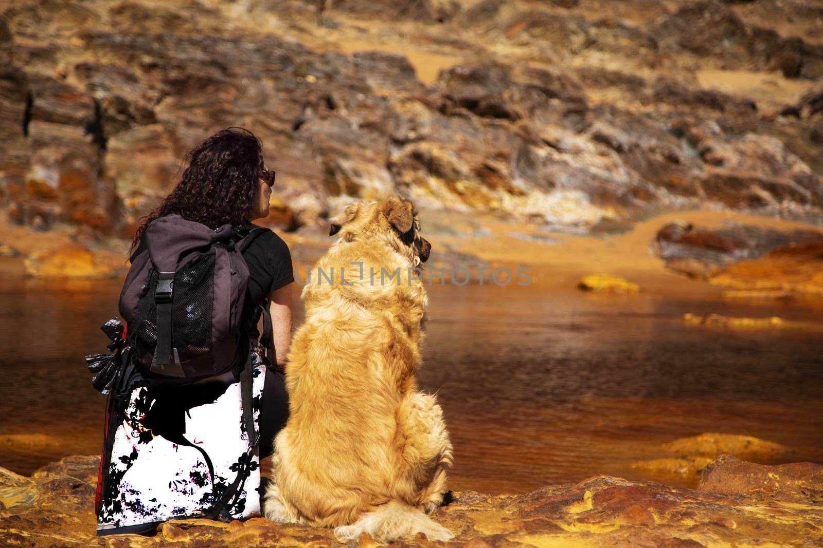 Woman sitting in the edge of Rio Tinto with her dog