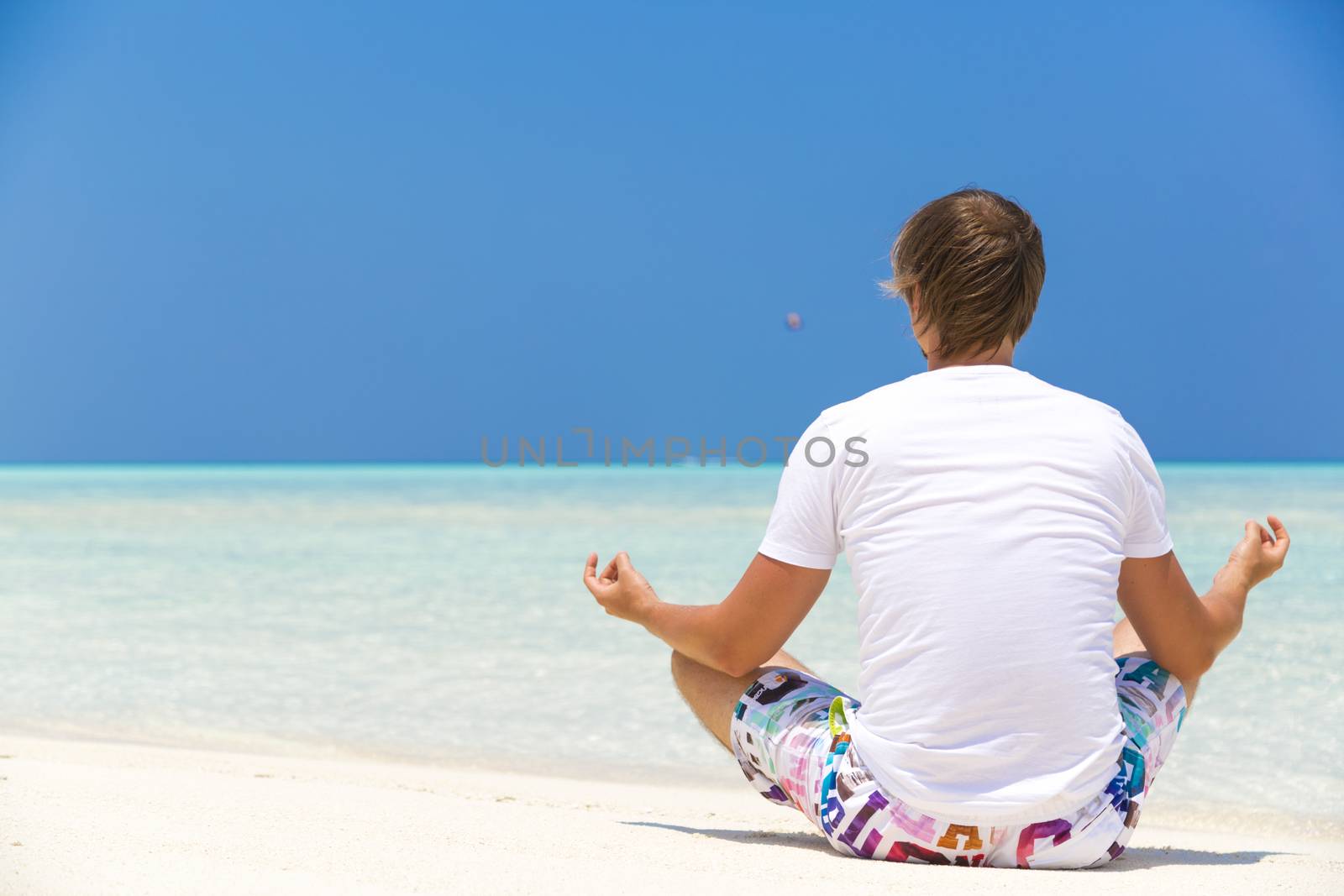 Man doing some relaxing exercises on the shore in Maldives.