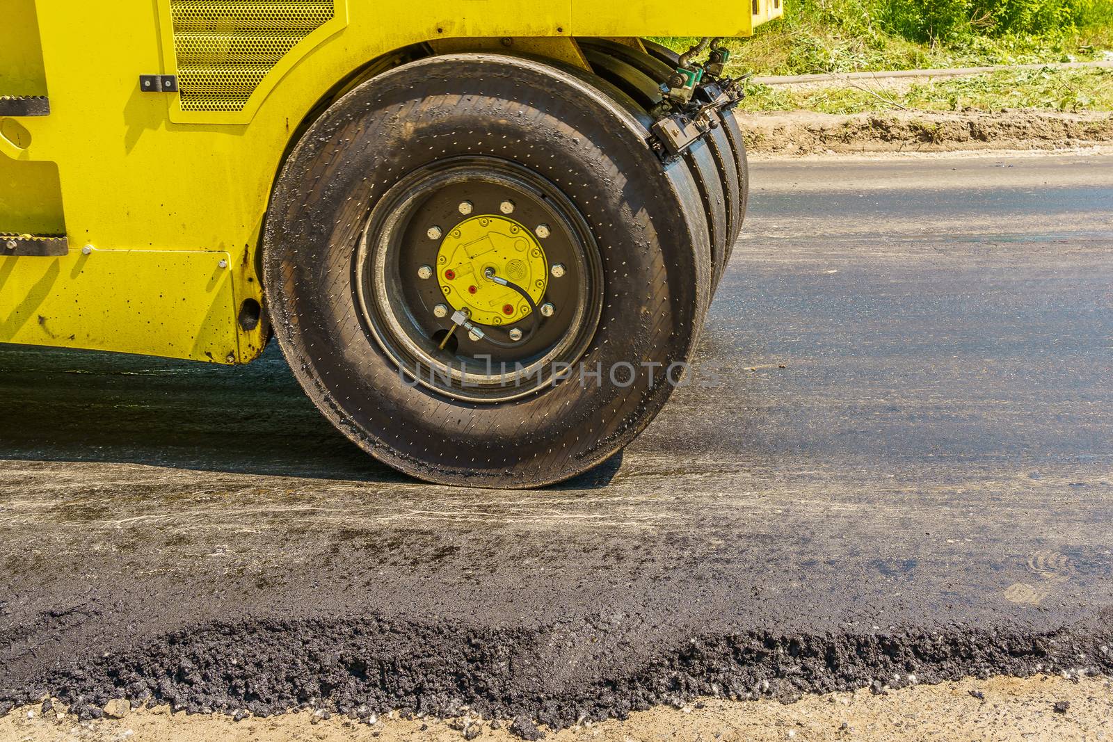 asphalt road roller smooths the road on a sunny day