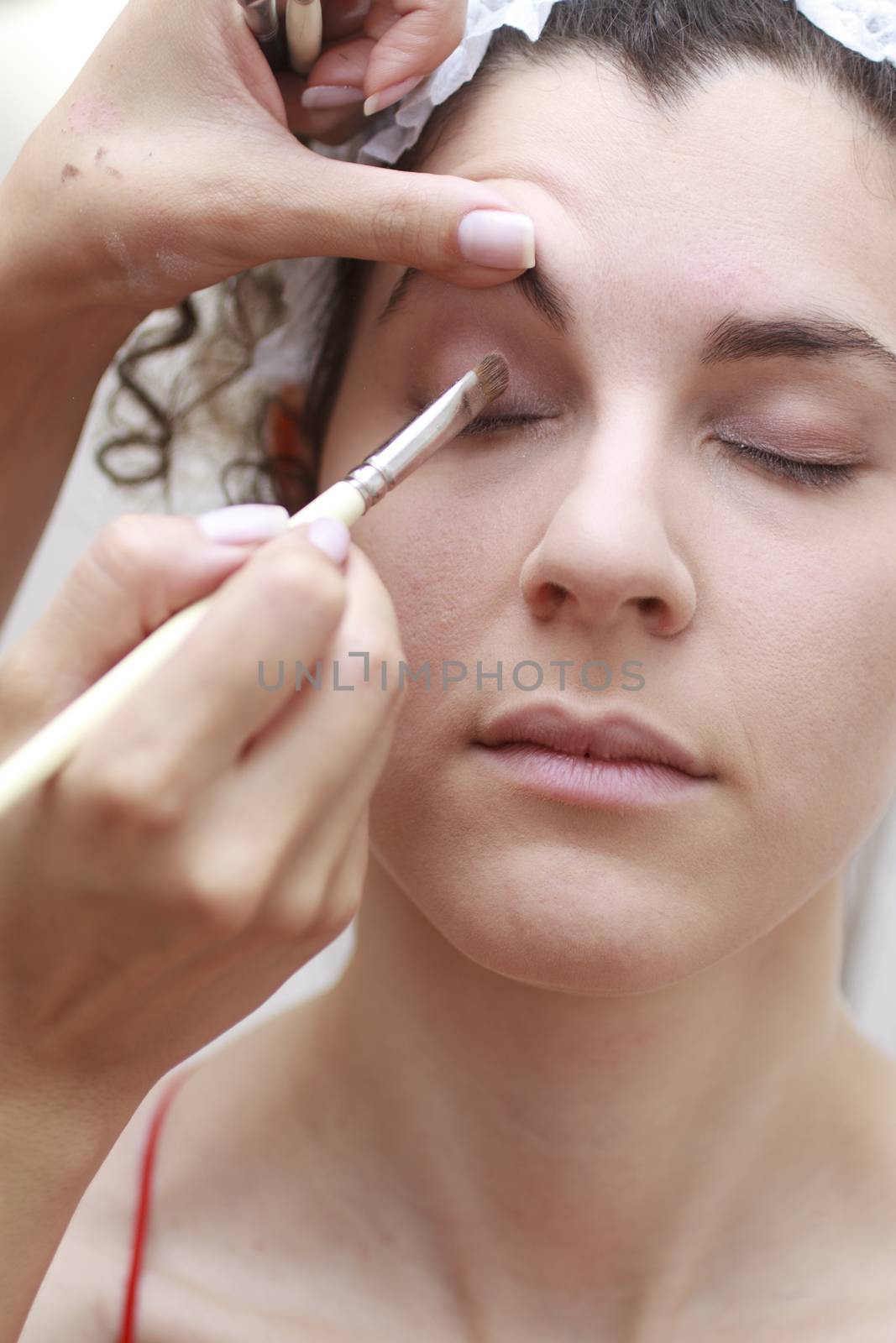 Young woman having make-up applied by a beautician.