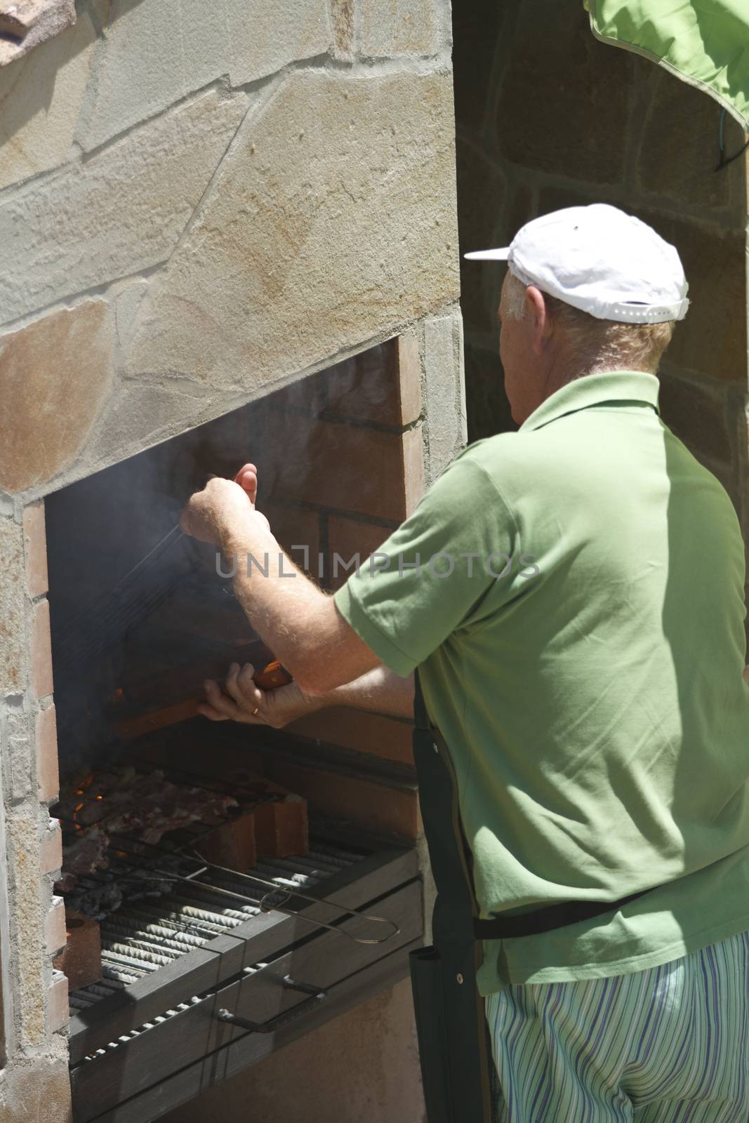 Senior man doing barbecue outdoors at beauty barbecue grill.