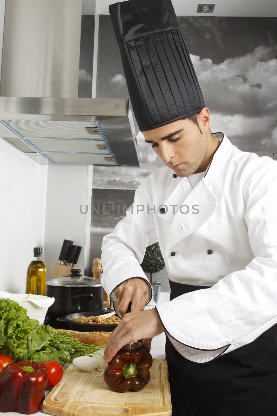 Chef chopping red pepper on cutting board.