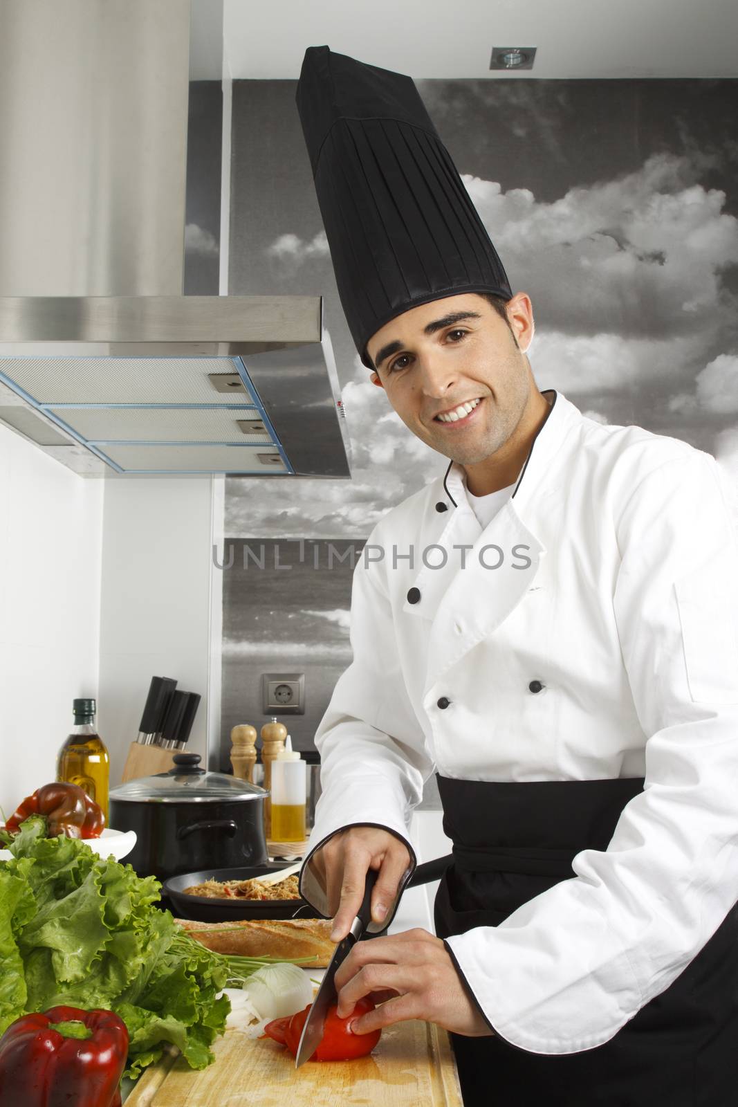 Chef chopping tomatoes on cutting board.