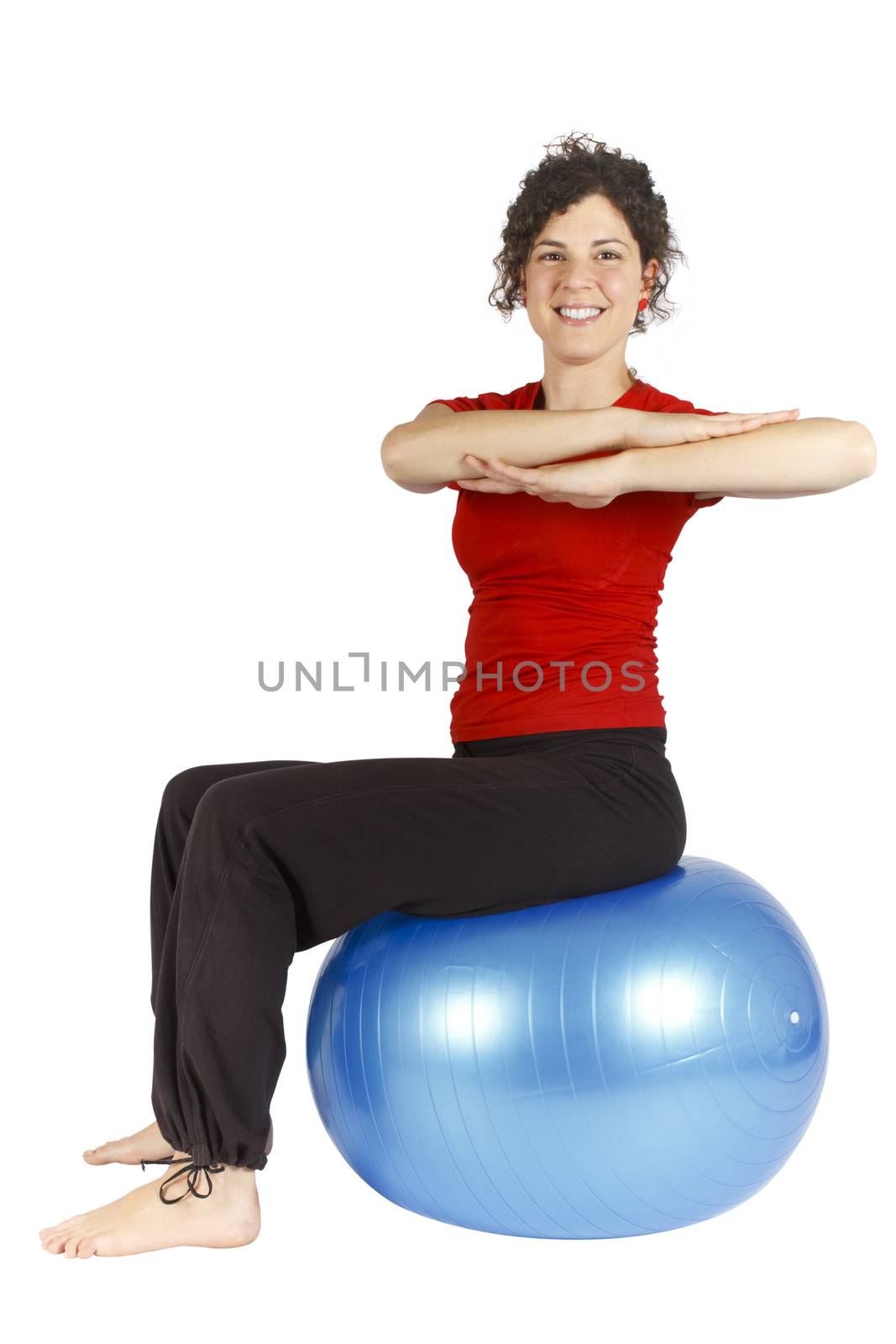 Smiling young woman sitting on a blue yoga ball doing an exercise.