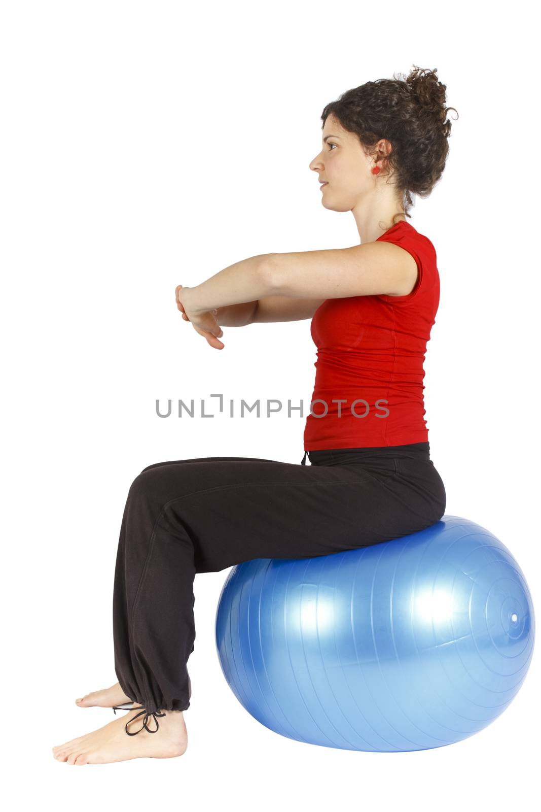Young woman sitting on a blue yoga ball doing an exercise.
