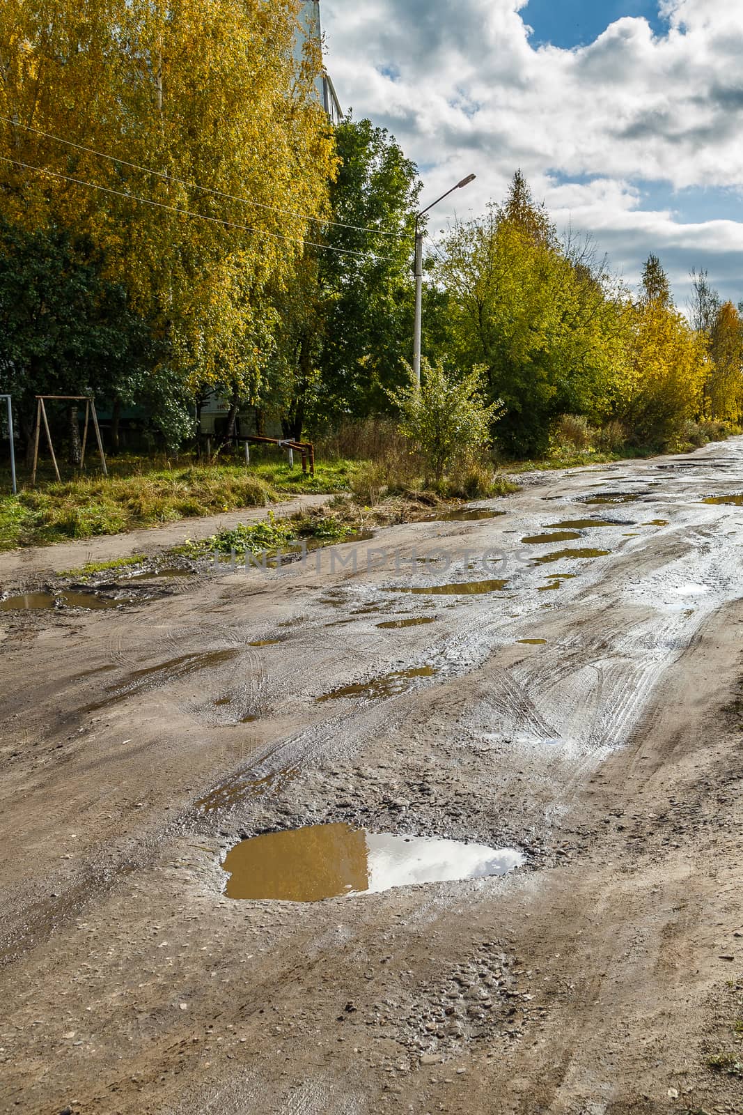 roadway in a provincial Russian city in poor condition, pits and dirt, vertical frame