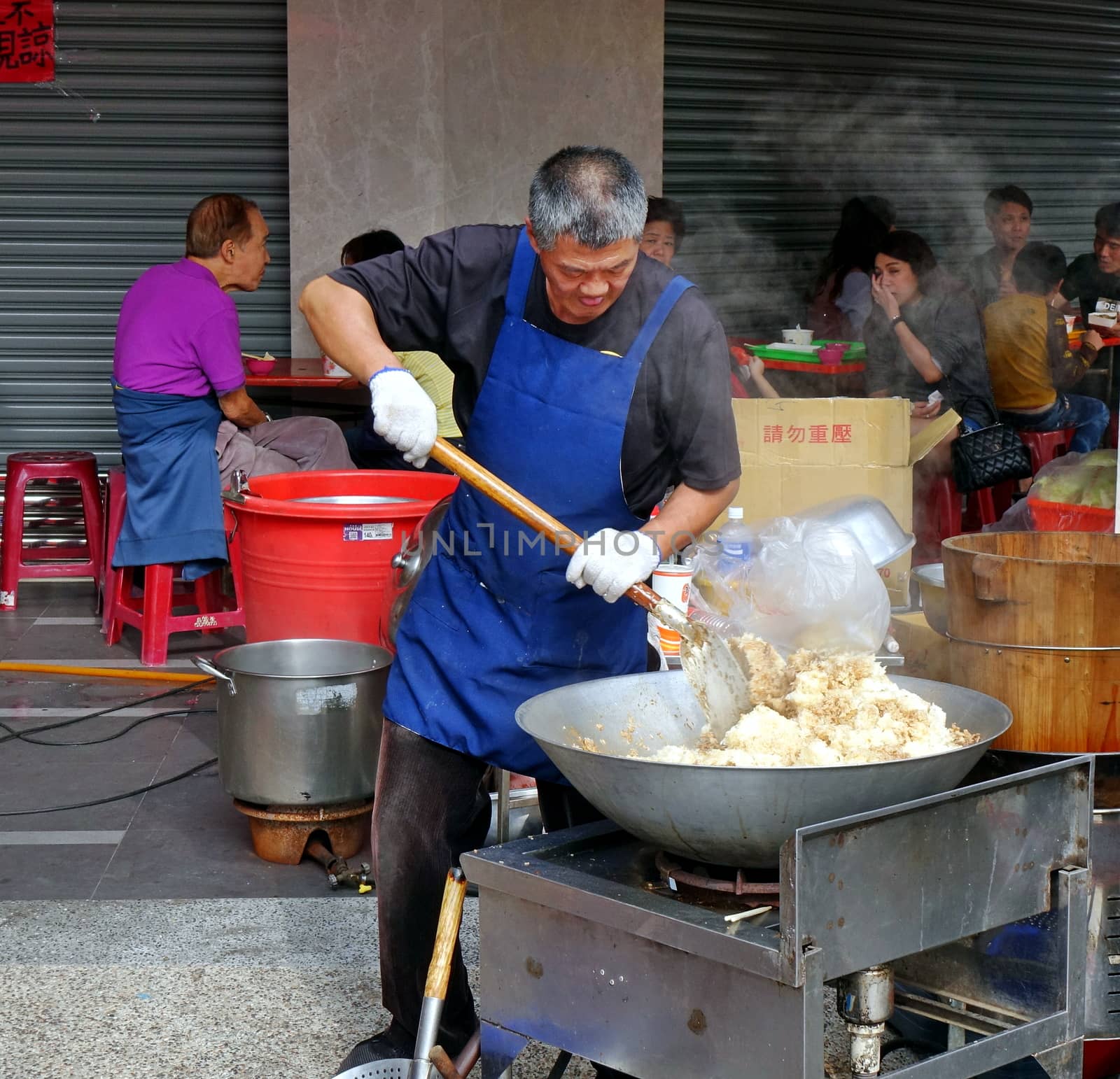 KAOHSIUNG, TAIWAN -- FEBRUARY 17, 2018: A man at an outdoor food stall cooks fried rice in a large wok.
