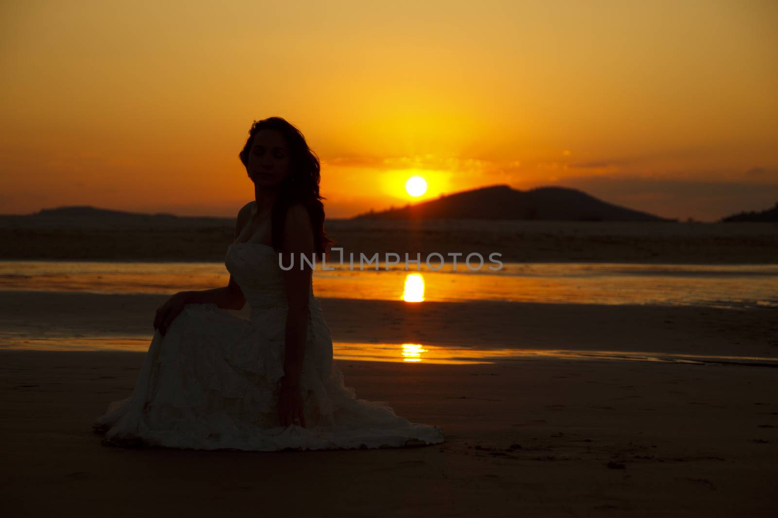 Bride contemplating beach at sunset. Low light