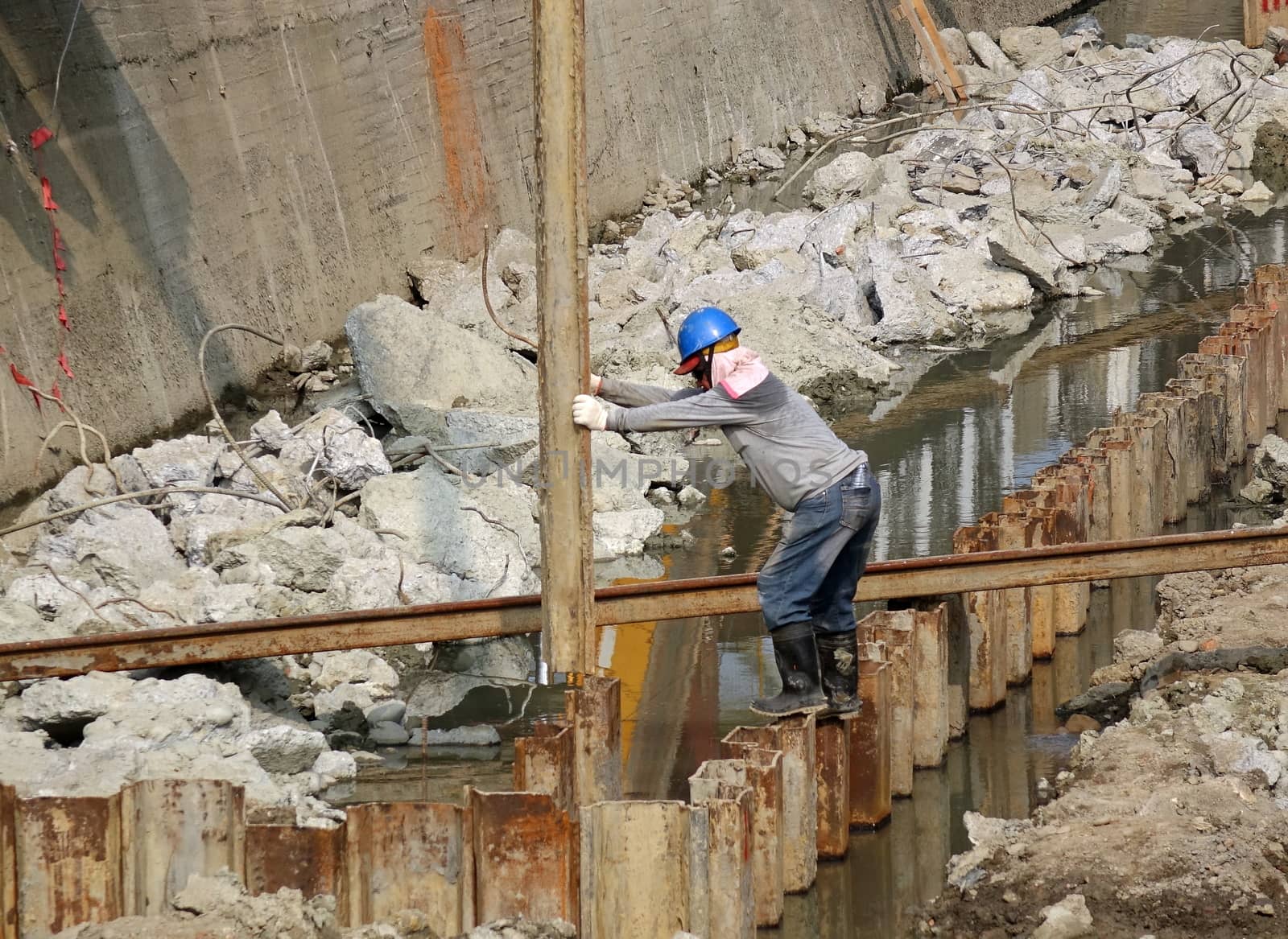 KAOHSIUNG, TAIWAN -- OCTOBER 10, 2018: A construction worker guides the placement of a steel girder to be driven into the ground by a pile driver.
