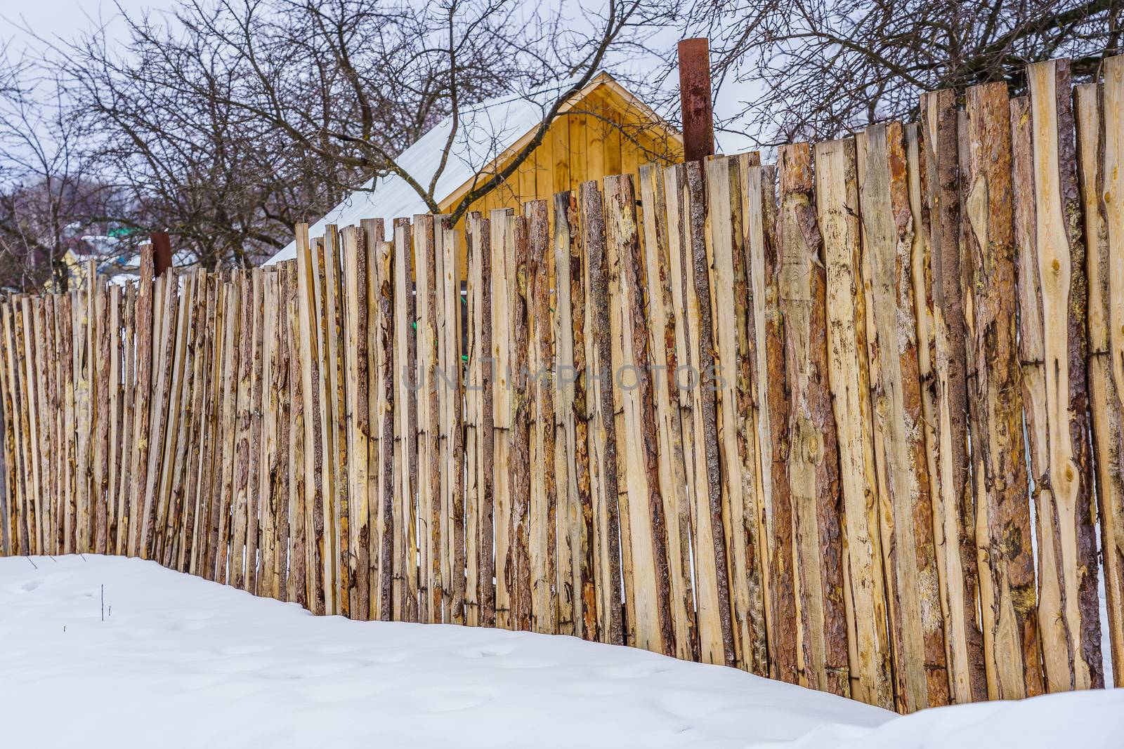 fence around the garden of unpainted boards on a winter day