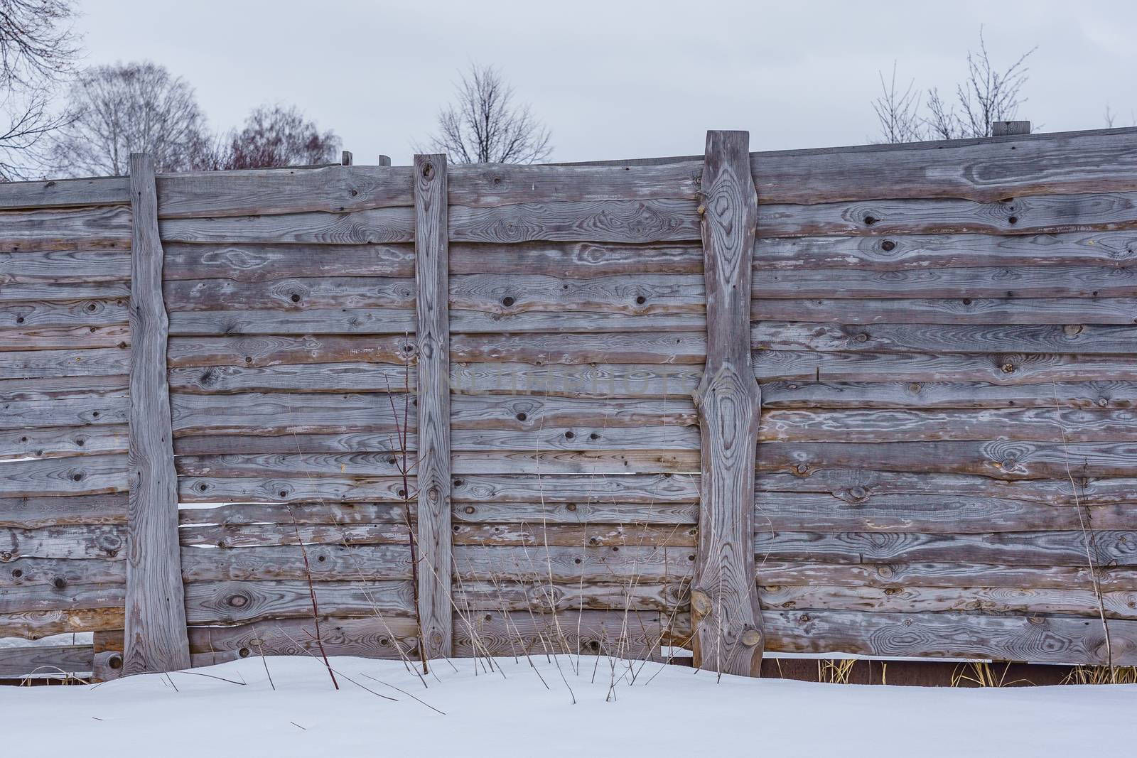 fence around the garden of unpainted boards on a winter day