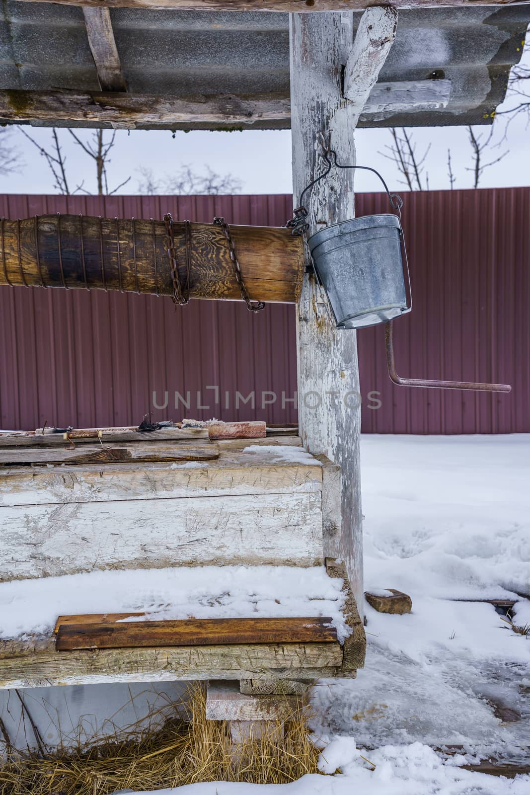 wooden well with a tin bucket, winter day