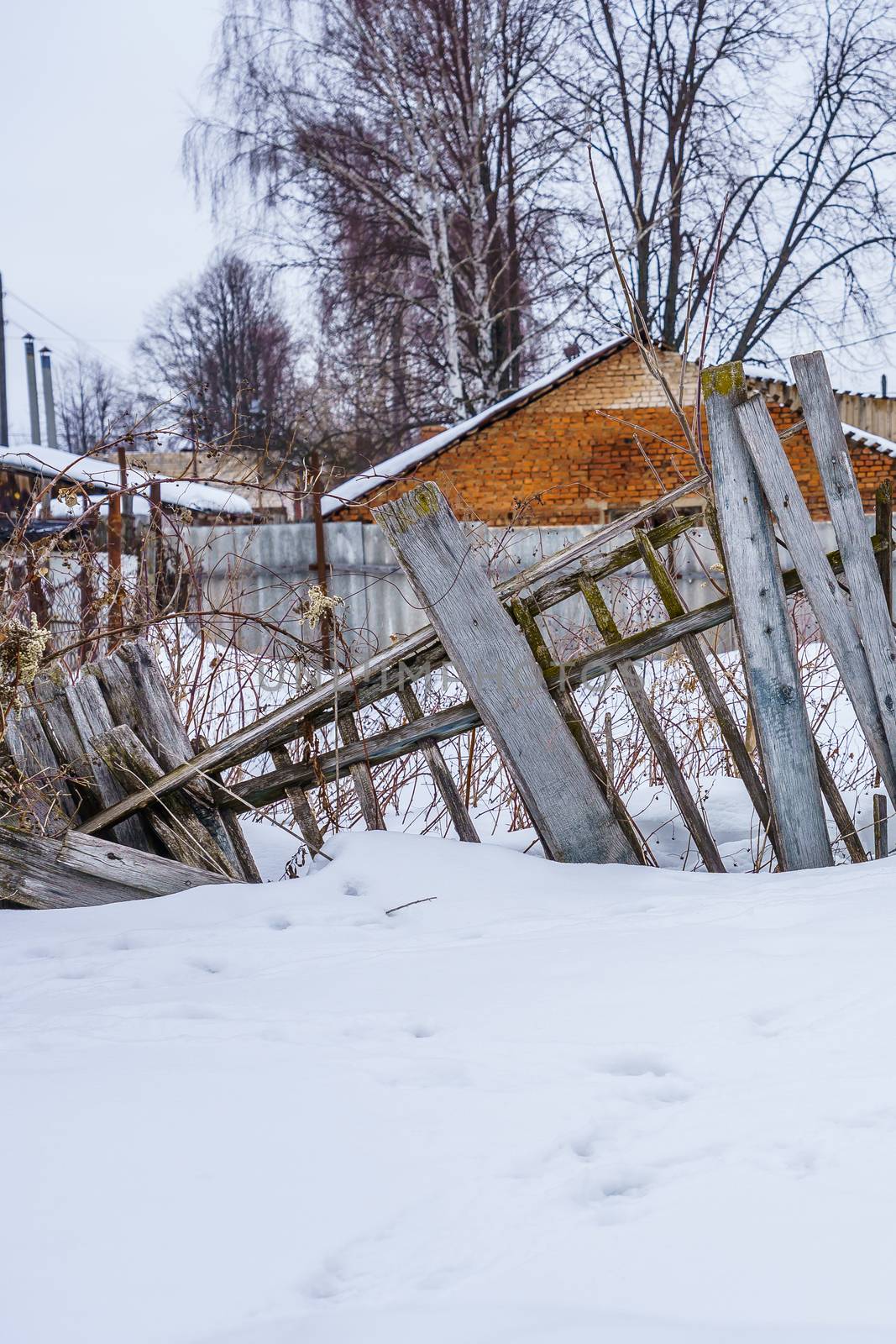 old fence from boards around the building, winter day