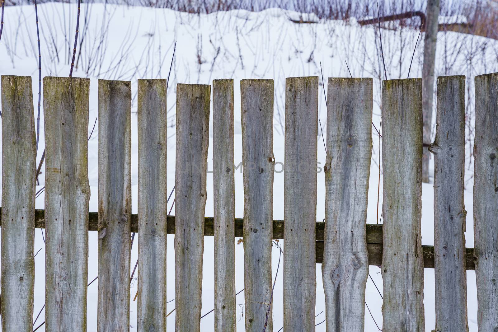 wooden fence of boards nailed to the crossbar on a winter day