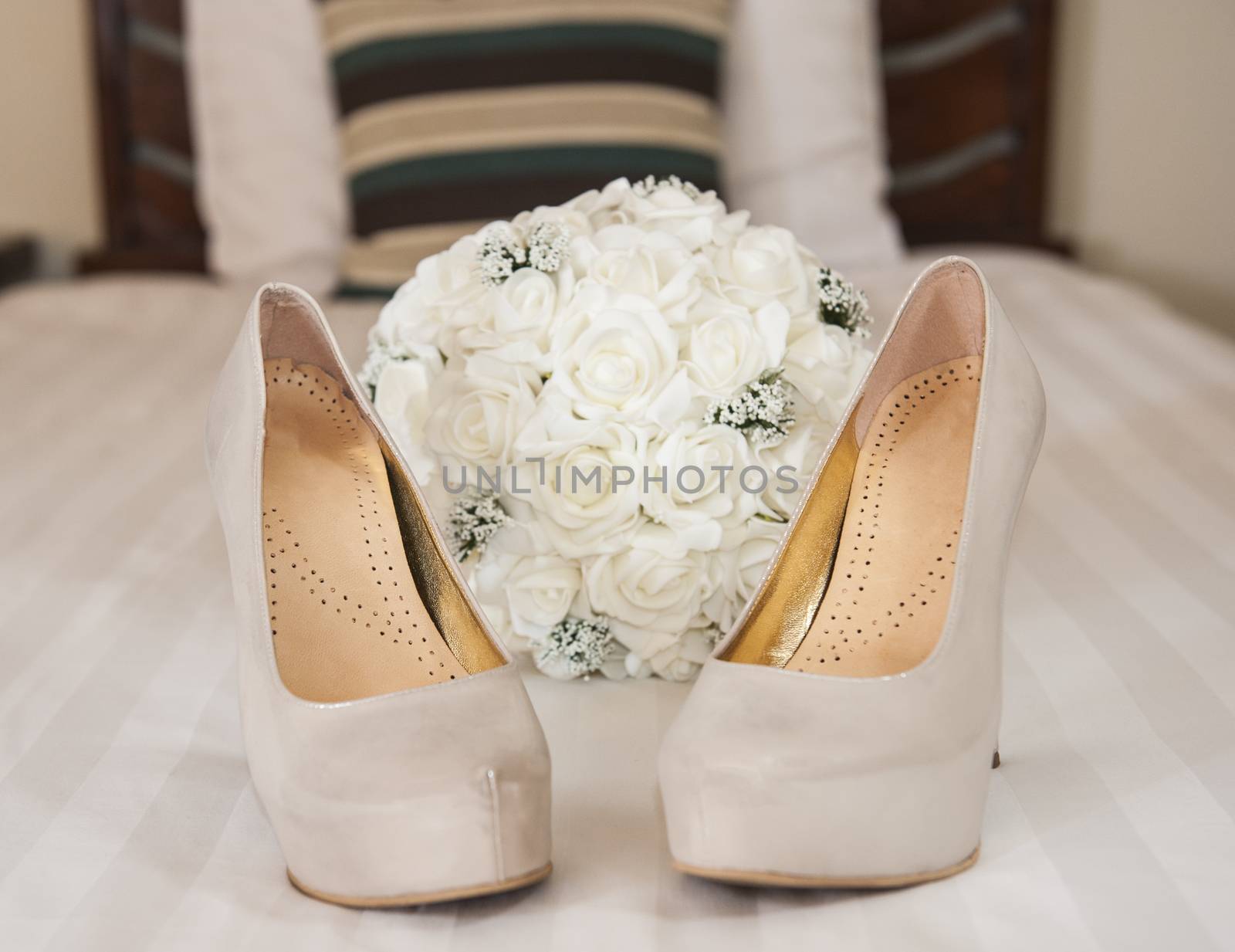 Closeup detail of bridal high heeled platform stiletto wedding shoes with flower bouquet