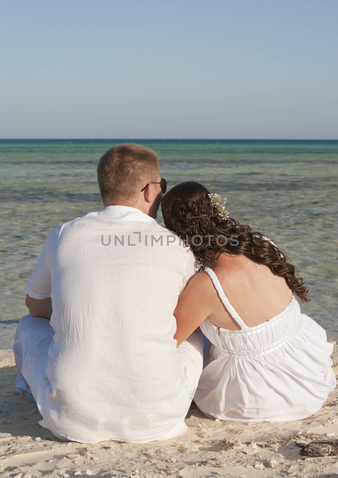 Young newly married couple sitting on a tropical beach