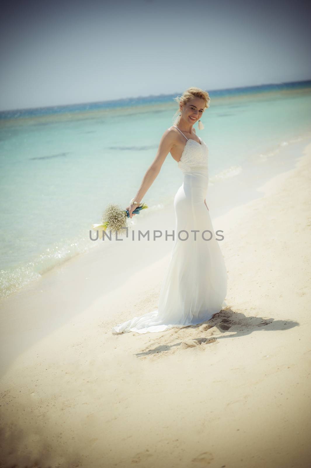 Beautiful woman bride at a tropical beach paradise on wedding day in white gown dress with ocean view vintage style photo