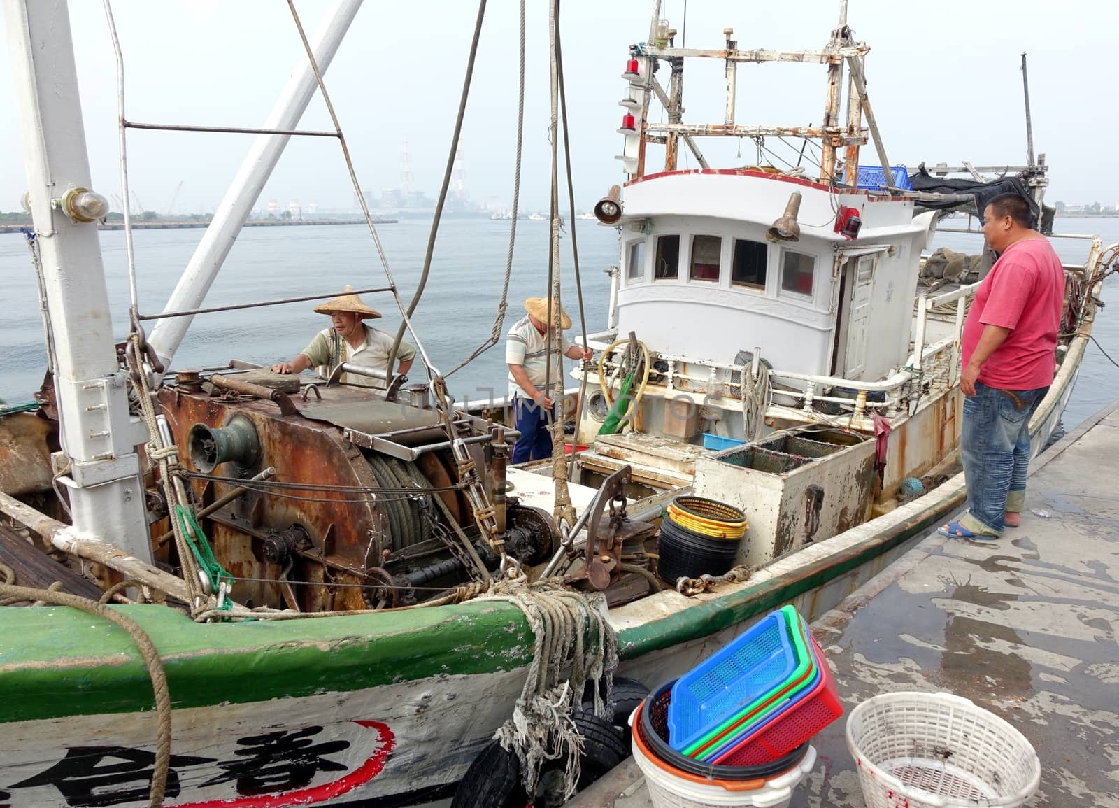 KAOHSIUNG, TAIWAN -- MAY 3, 2014: Fishermen on board a boat docked at Sinda Fishing Port prepare to unload their catch.