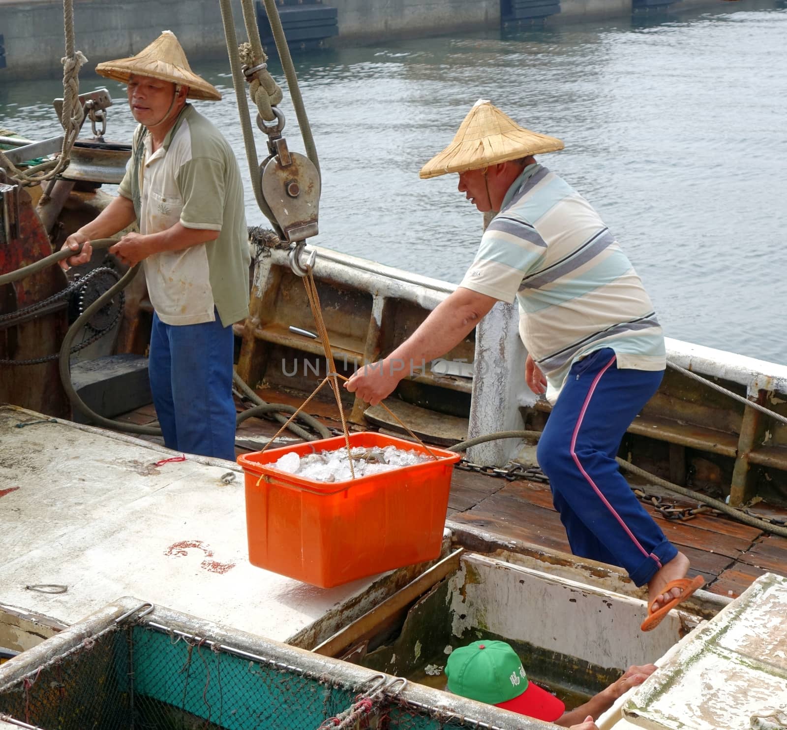 KAOHSIUNG, TAIWAN -- MAY 3, 2014: Fishermen on board a boat docked at Sinda Fishing Port unload their catch.