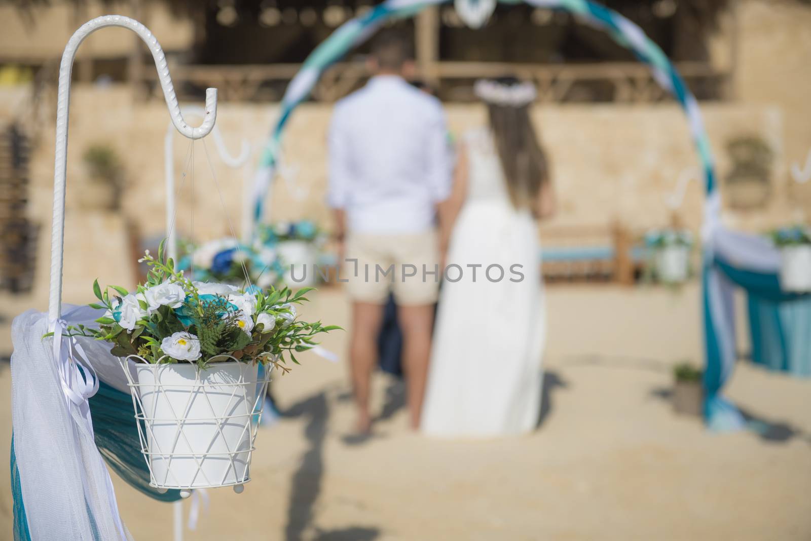 Setup of wedding day marriage couple ceremony aisle with drapes and arch on sandy tropical beach paradise