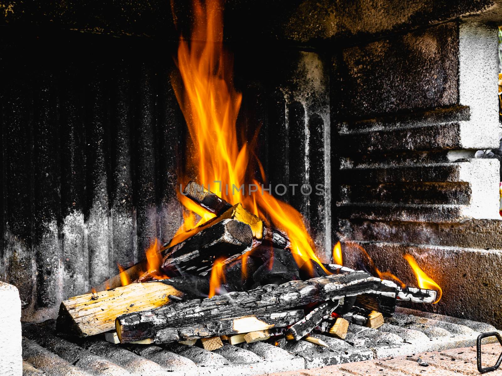 Preparation of a BBQ - wood piled up - fire reaching maximum heat and nearly ready to put charcoal on