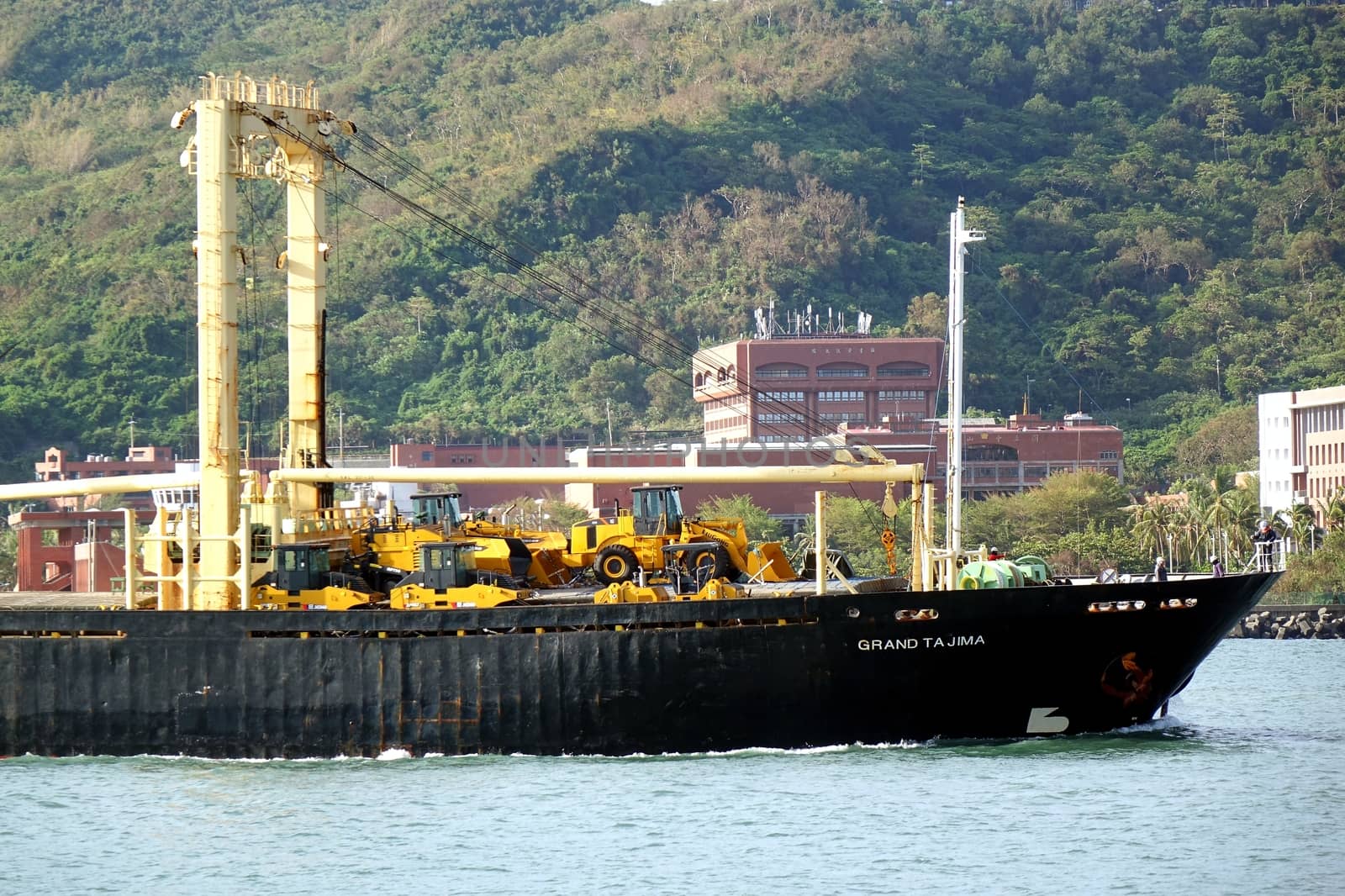 KAOHSIUNG, TAIWAN -- AUGUST 12, 2015: The Panamanian freighter Grand Tajima enters Kaohsiung Port with a cargo of construction equipment and excavators.
