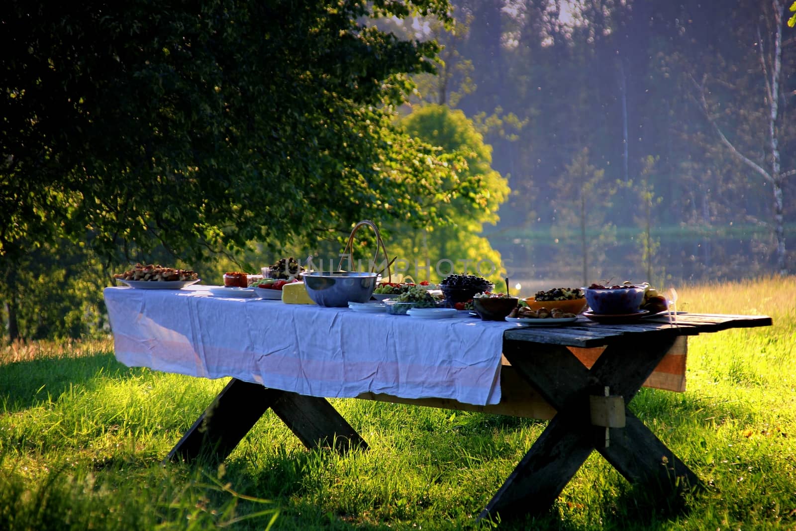 Wooden table under oaks with traditional Latvian food. Old Latvian culture tradition LIGO. Midsummer night celebrating in Latvia.