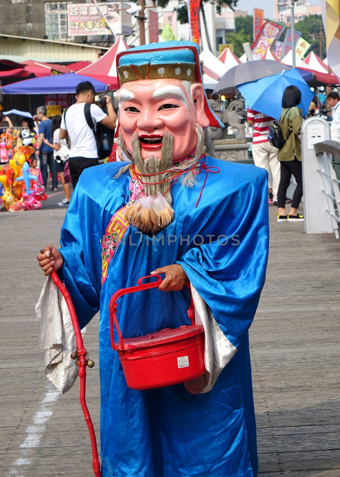 KAOHSIUNG, TAIWAN -- OCTOBER 17, 2015: A man dressed up as the traditional Chinese God of Wealth begs for lucky charm donations.