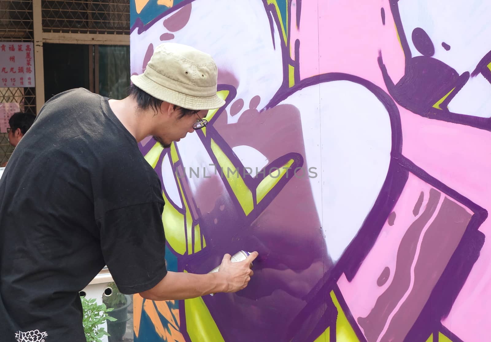 KAOHSIUNG, TAIWAN -- JULY 14, 2018: An artist sprays paint on a mural during the 2018 Street Art Festival.
