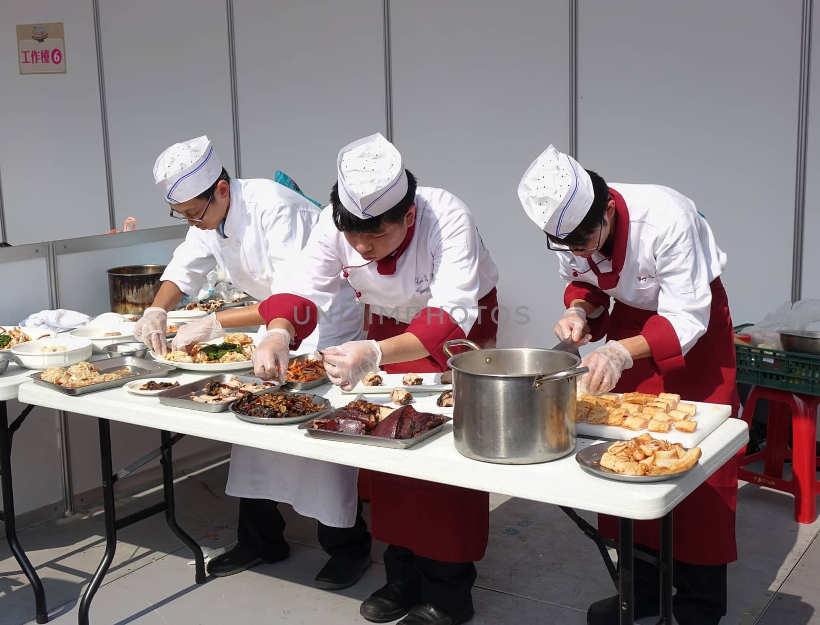 KAOHSIUNG, TAIWAN -- NOVEMBER 28, 2015: Three chefs prepare dishes for the cooking competition during the 2015 Hakka Food Festival, which is a yearly public outdoor event.
