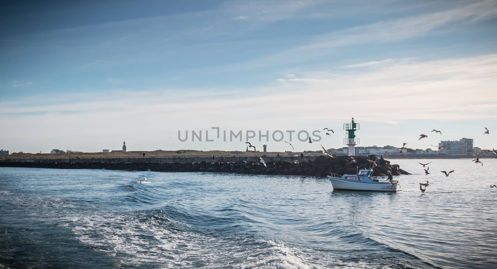 Saint Gilles Croix de Vie, France - September 16, 2018: Small fishing boat entering the harbor accompanied by seagulls on a summer day