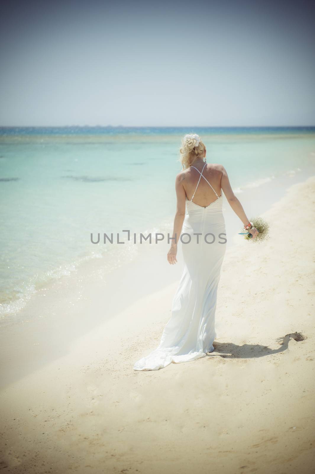 Beautiful woman bride at a tropical beach paradise on wedding day in white gown dress with ocean view vintage style photo