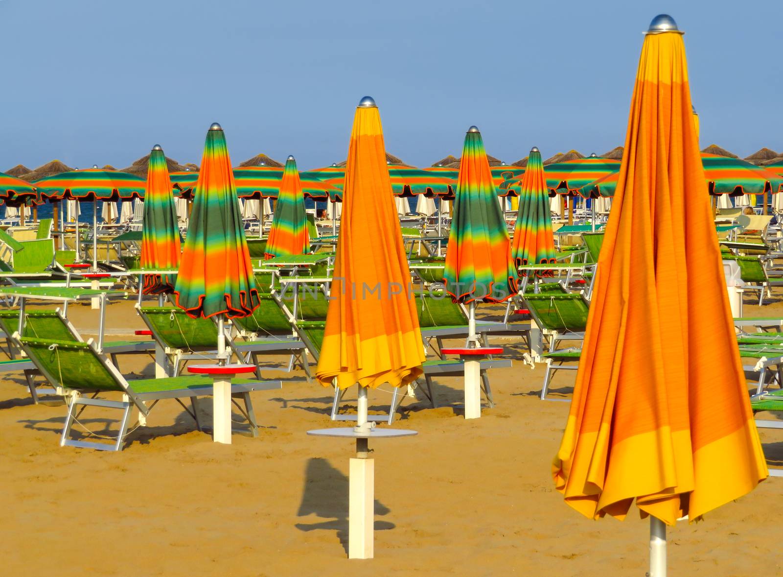 Orange closed umbrellas on the beach of Rimini in Italy