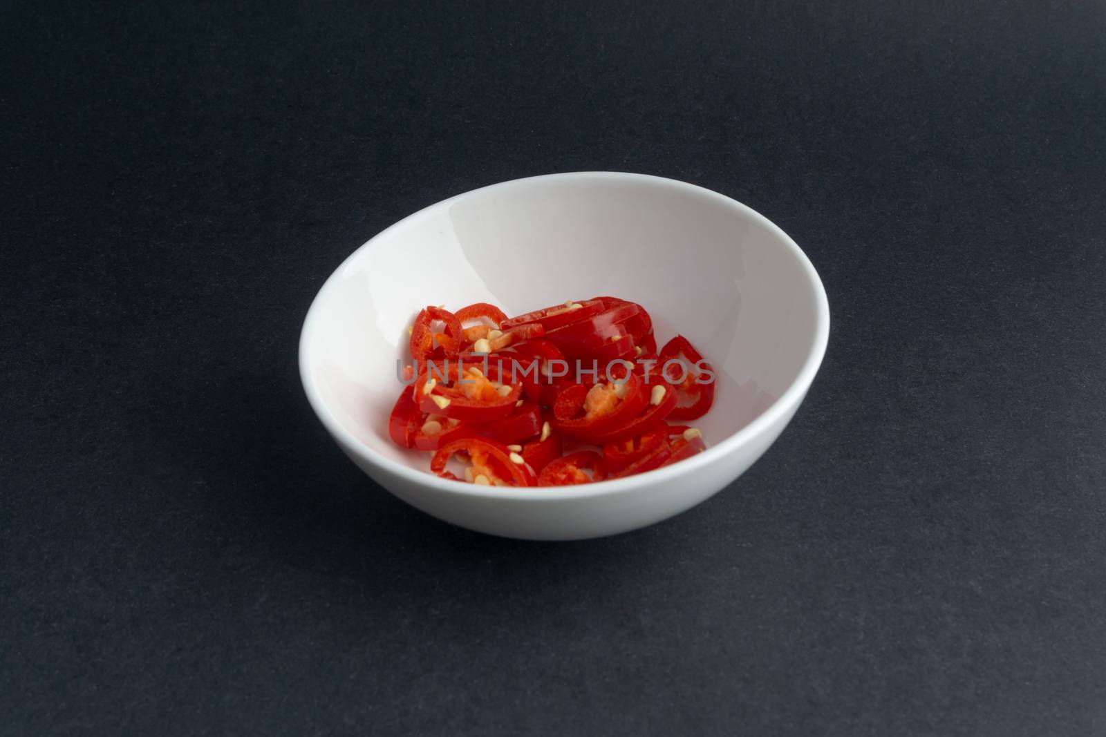 Spicy slice of red chillies closeup on black background by silverwings