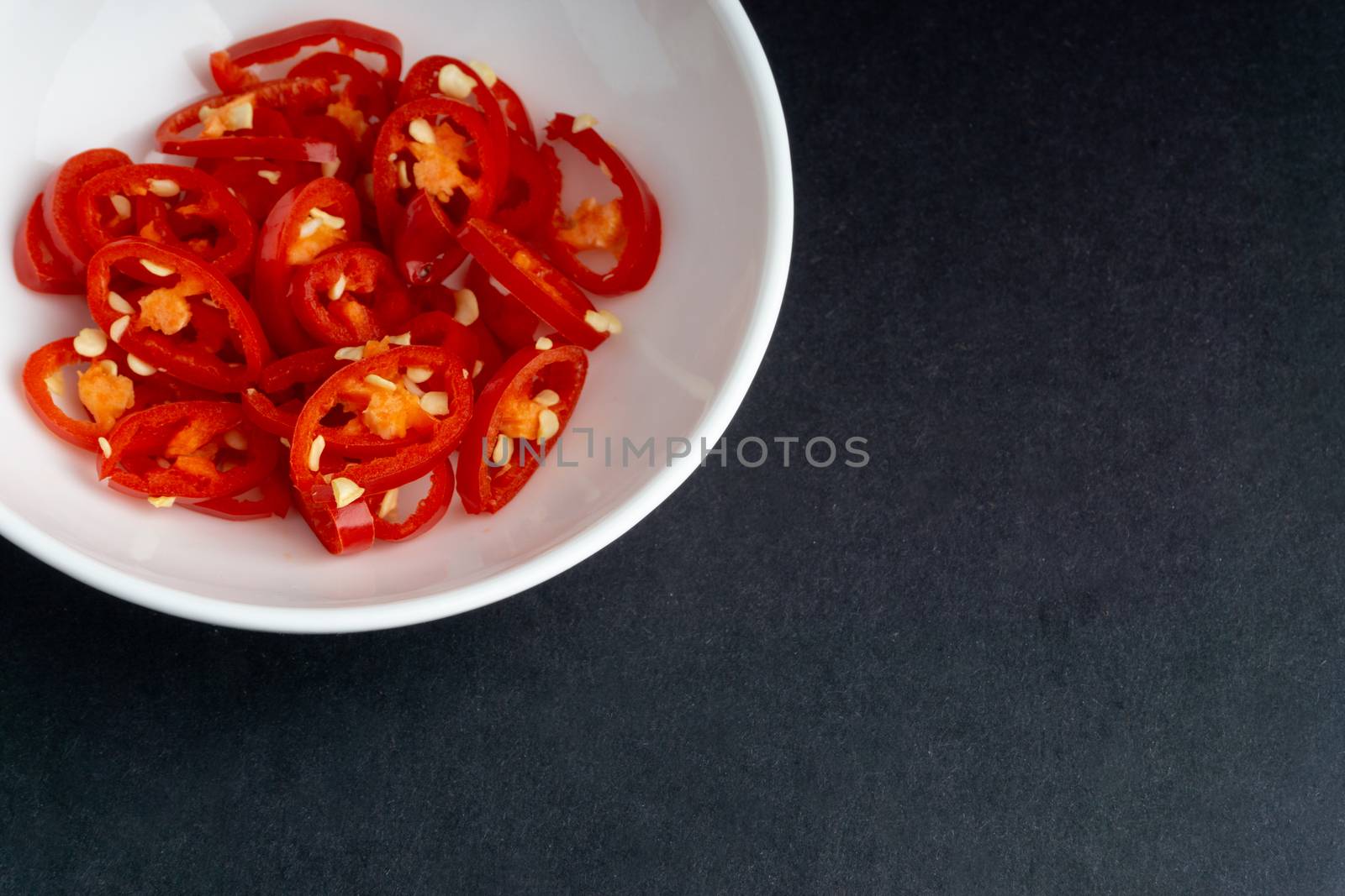 Spicy slice of red chillies closeup on black background