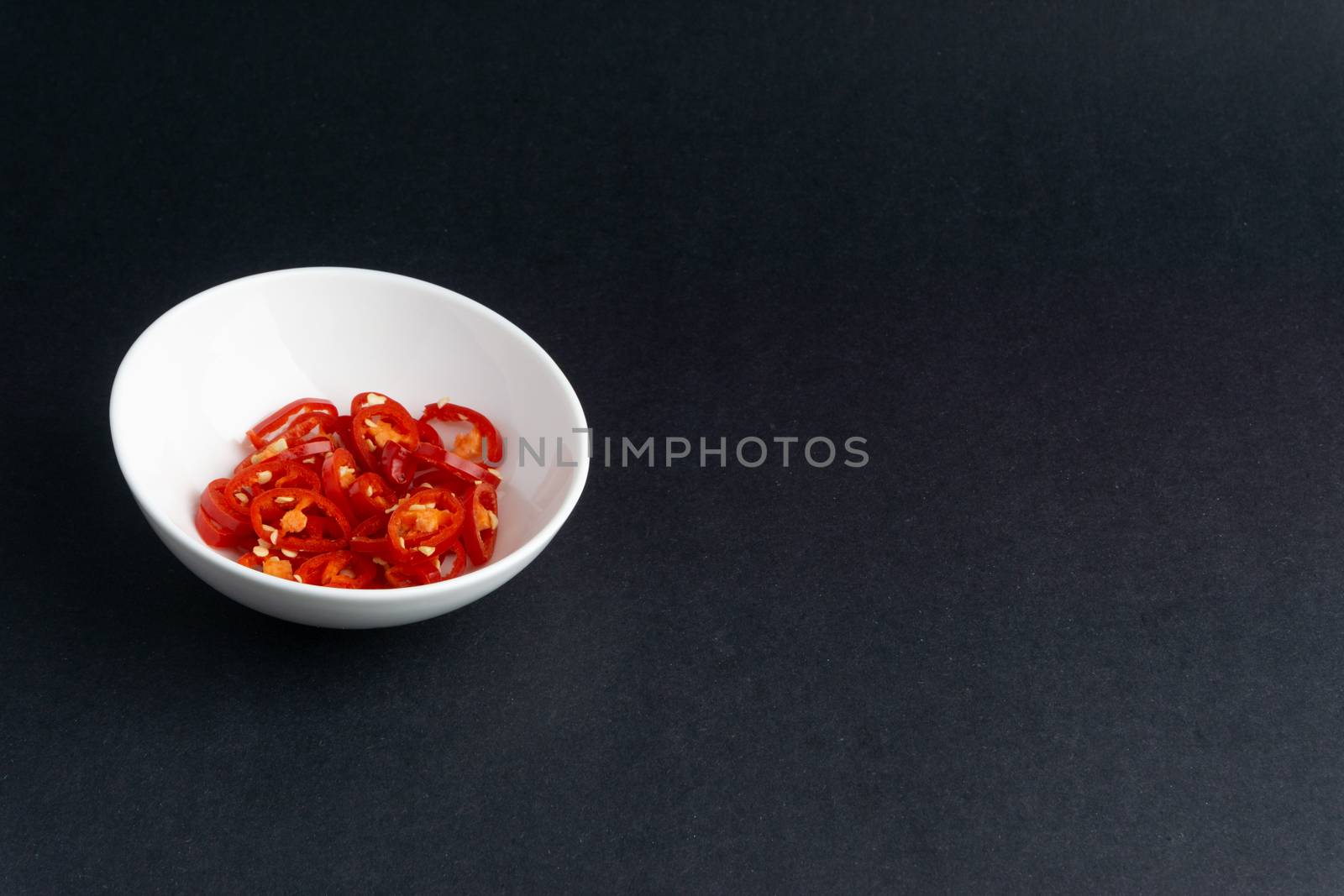 Spicy slice of red chillies closeup on black background by silverwings