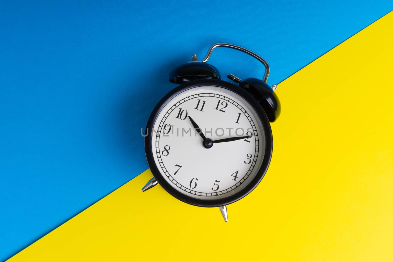 Alarm clock on a blue and yellow background. Business Concept